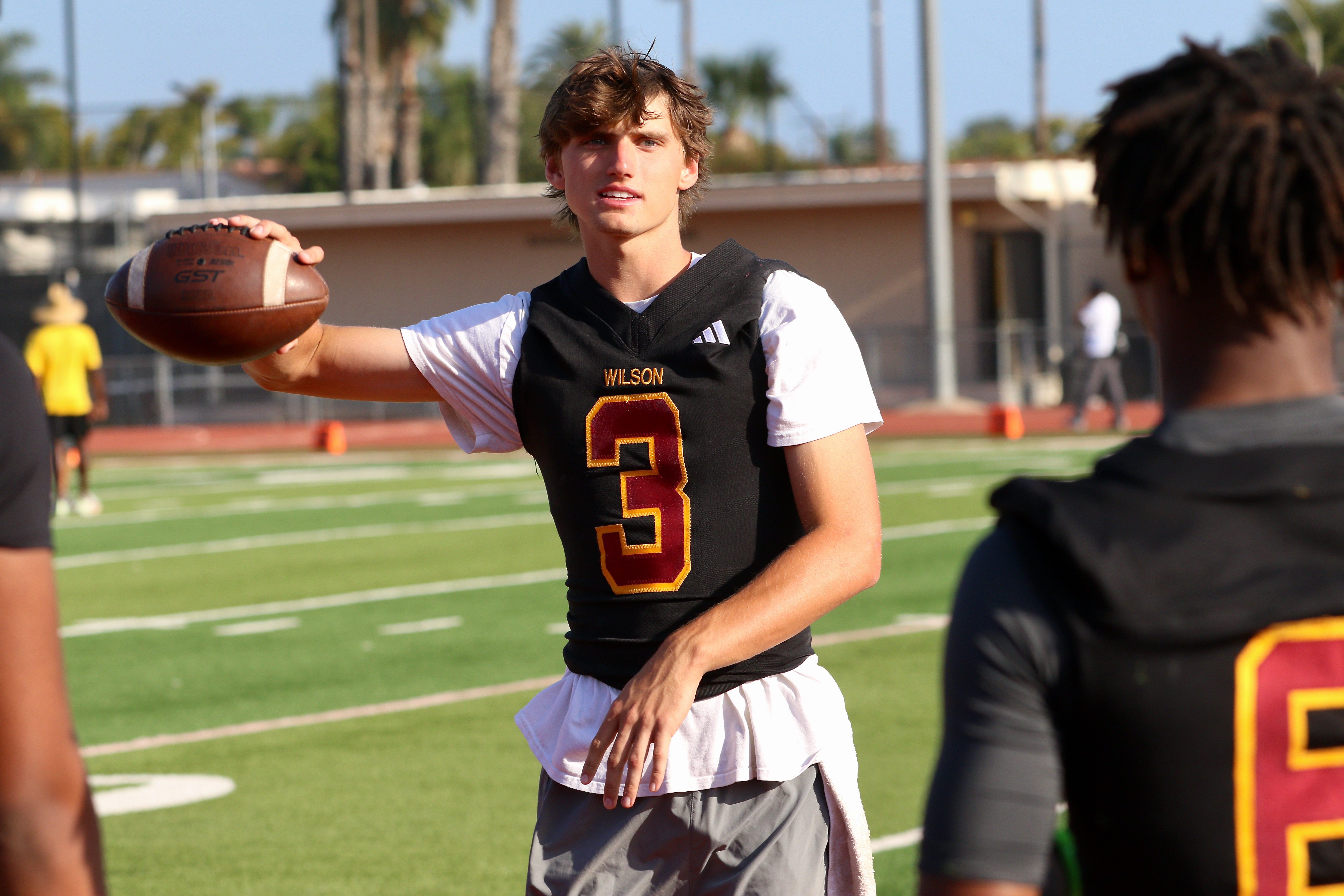Wilson quarterback Logan Trafas chats with teammates during a spring...