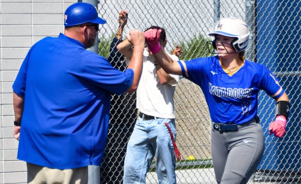 La Mirada head coach Brent Tuttle congratulates Riley Hilliard (11) after hitting a home run on the first inning against Warren in their Gateway League softball game at La Mirada High School on Thursday April 30, 2026. La Mirada defeated Warren 6-0 to clinch the Gateway League Championship. (Photo by Keith Durflinger, Contributing Photographer)