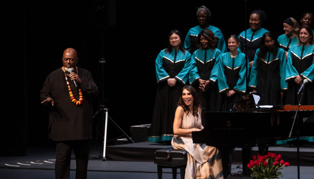 Pianist Lara Downes laughs at a grand piano while sharing the stage with artistic director Terrance Kelly and members of the Oakland Interfaith Gospel Choir during their performance at Zellerbach Hall.