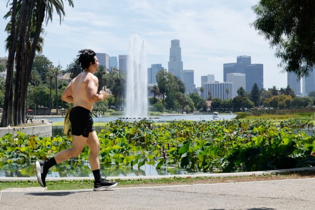 A runner passes by the Los Angeles skyline at Echo Park Lake amid a heat wave on Aug. 21, 2025. (Carlin Stiehl/Los Angeles Times/TNS)