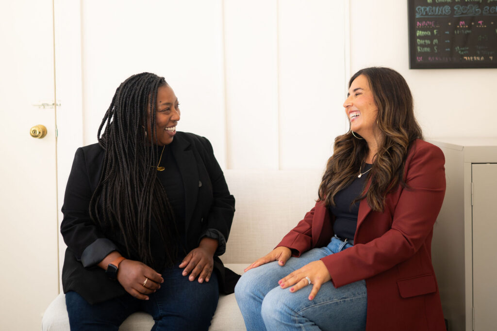 two women look at each other and smile
