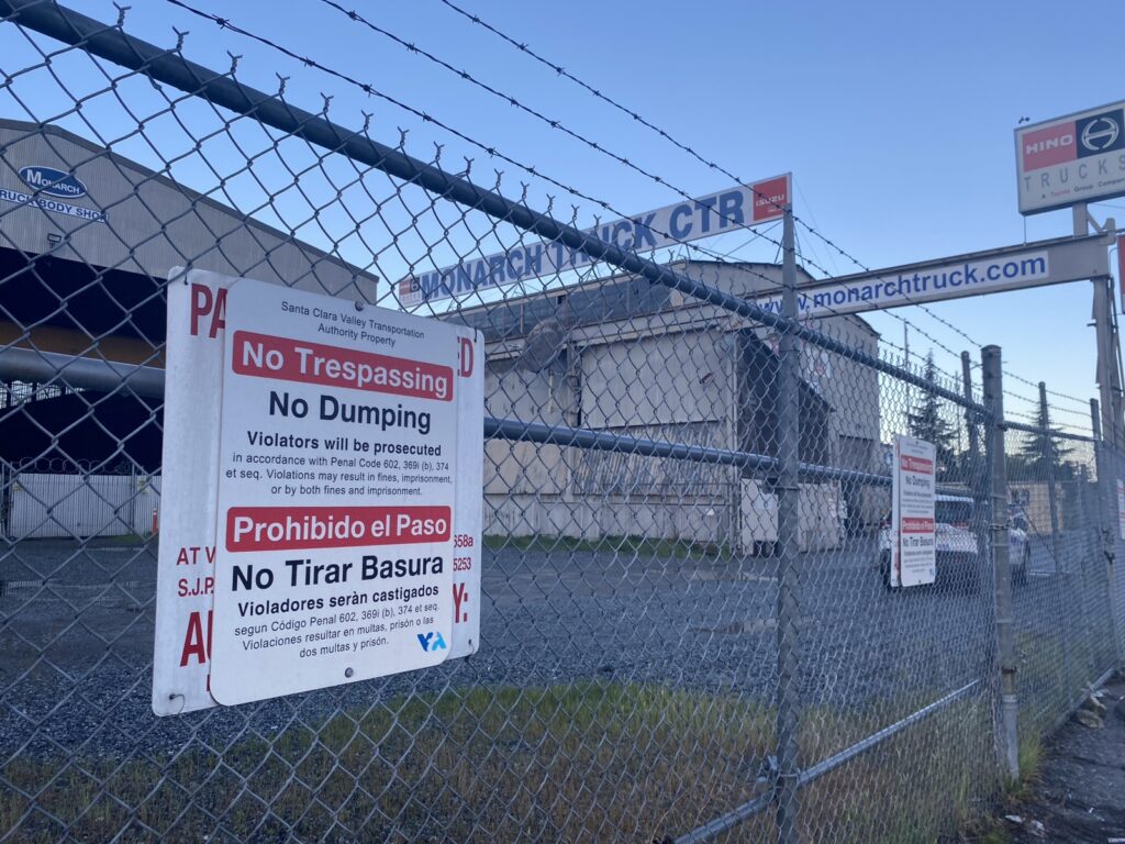 An industrial warehouse locked behind a chain fence.