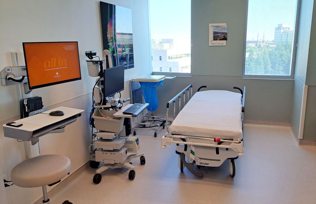 Image of a patient bed and medical equipment inside a room with a view of downtown Fresno