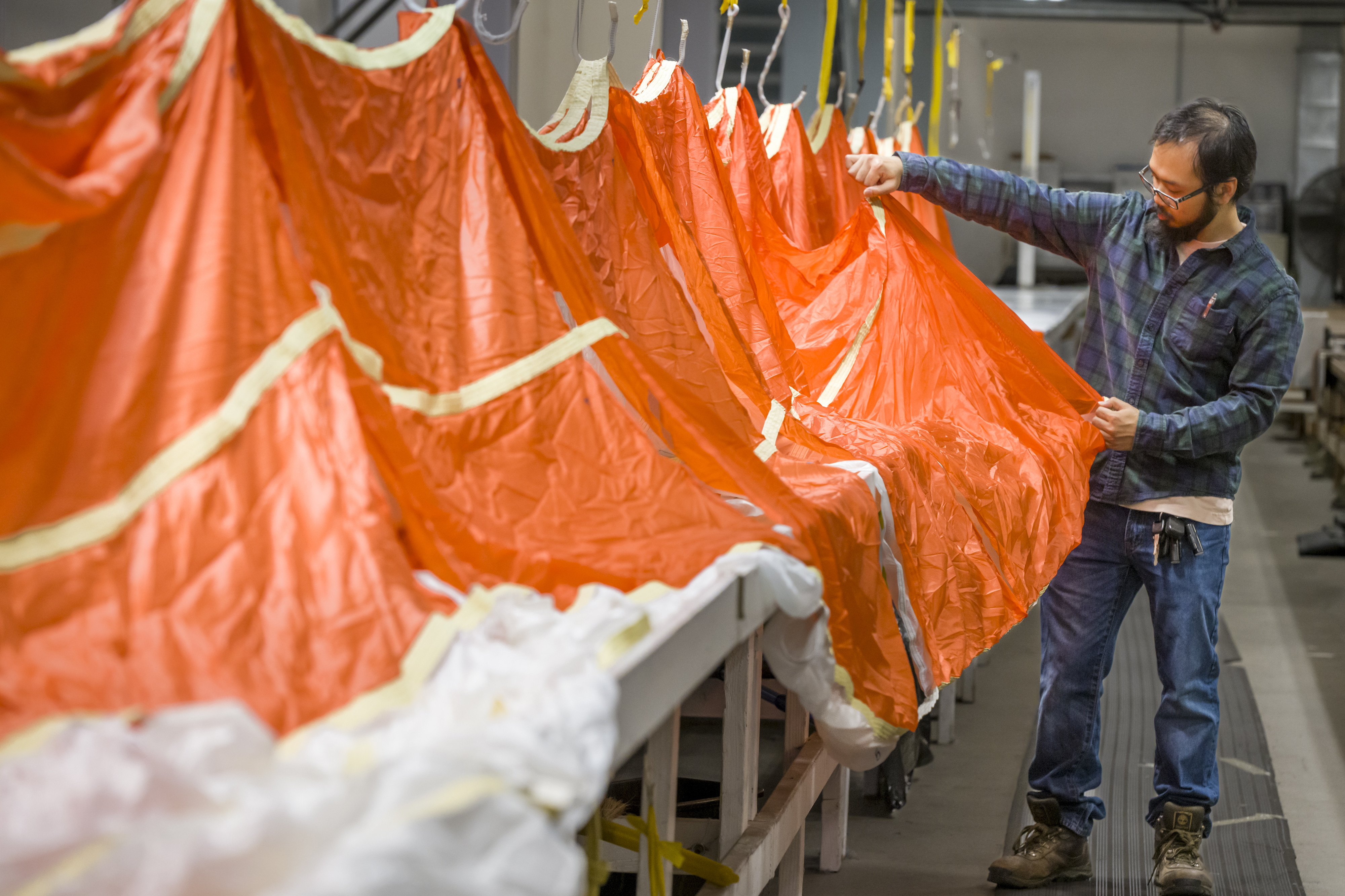 Parachute inspector Anthony-Minh Nguy examines a parachute to be used...