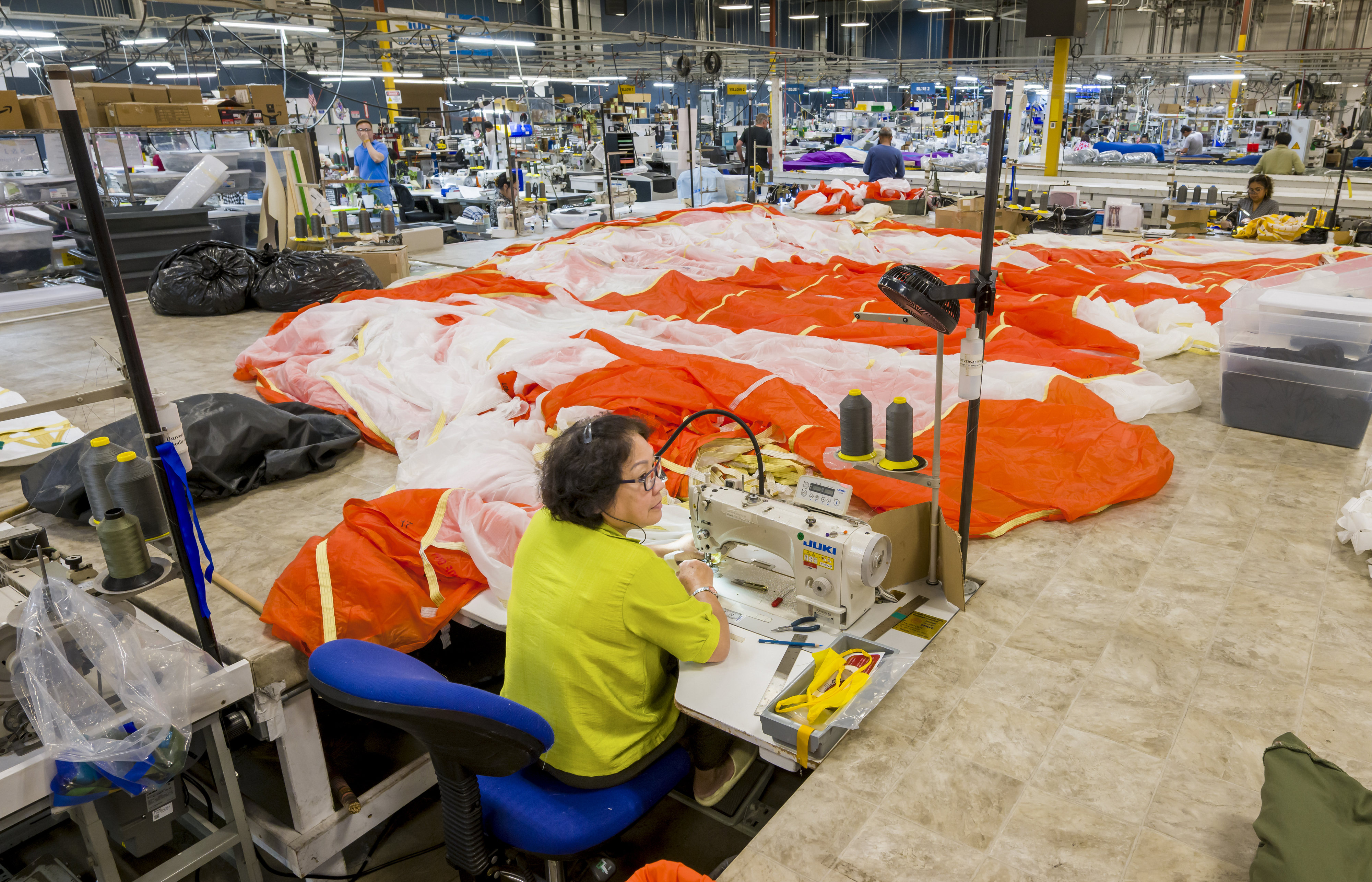 A sewing machine operator works on one of three parachutes...