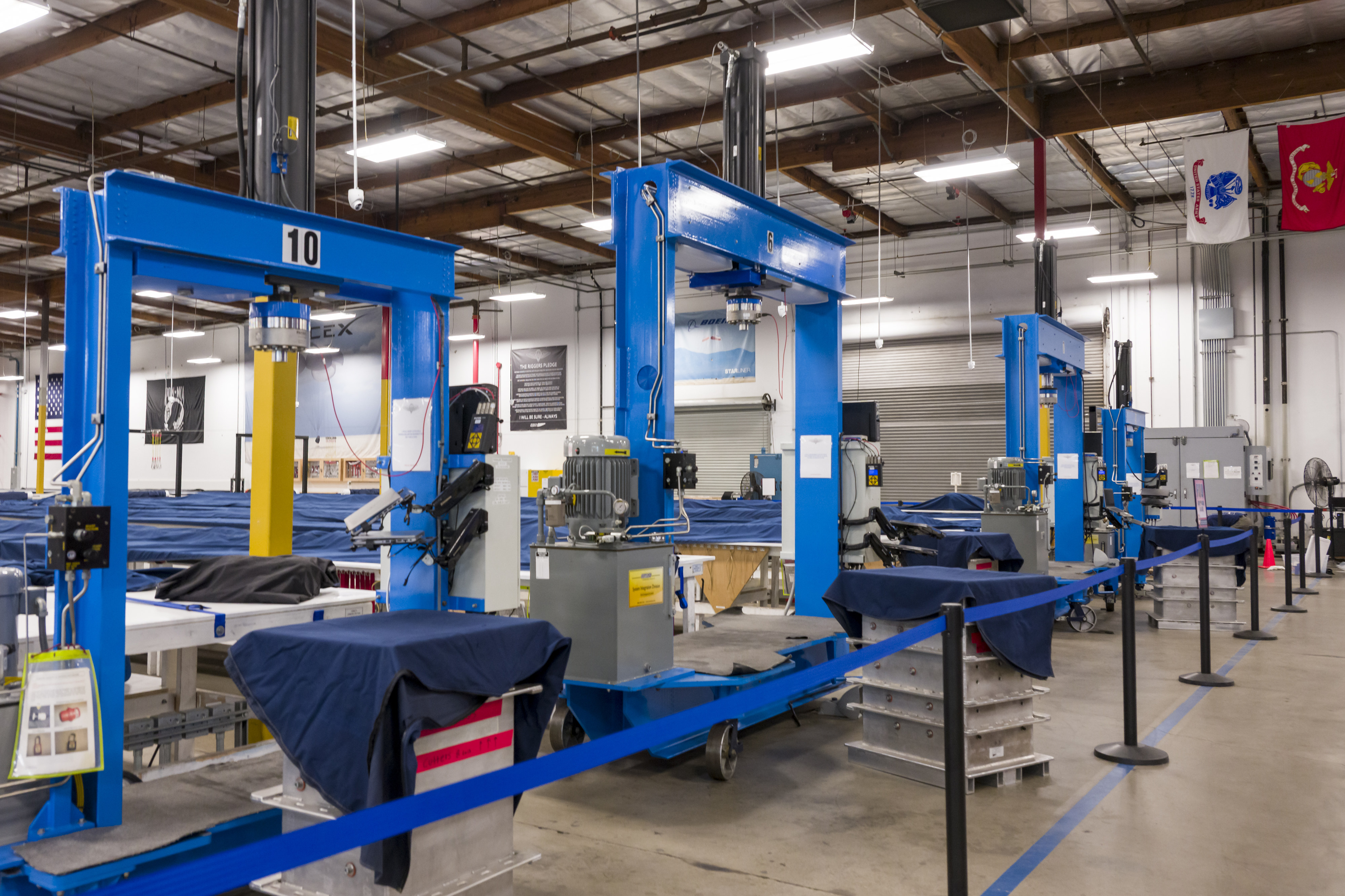 Giant blue steel frames support the hydraulic presses that compress...