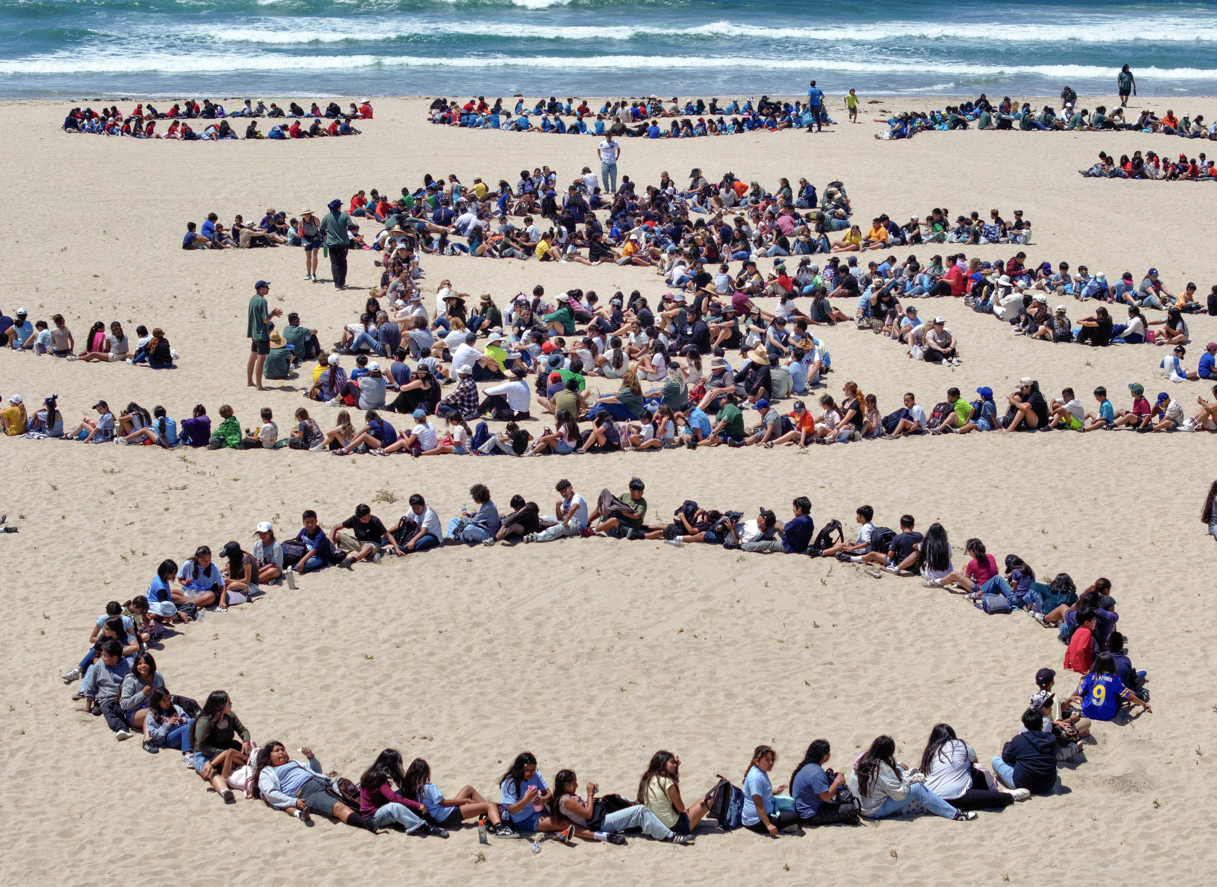 Over 1,000 kids form a giant artwork in the sand...