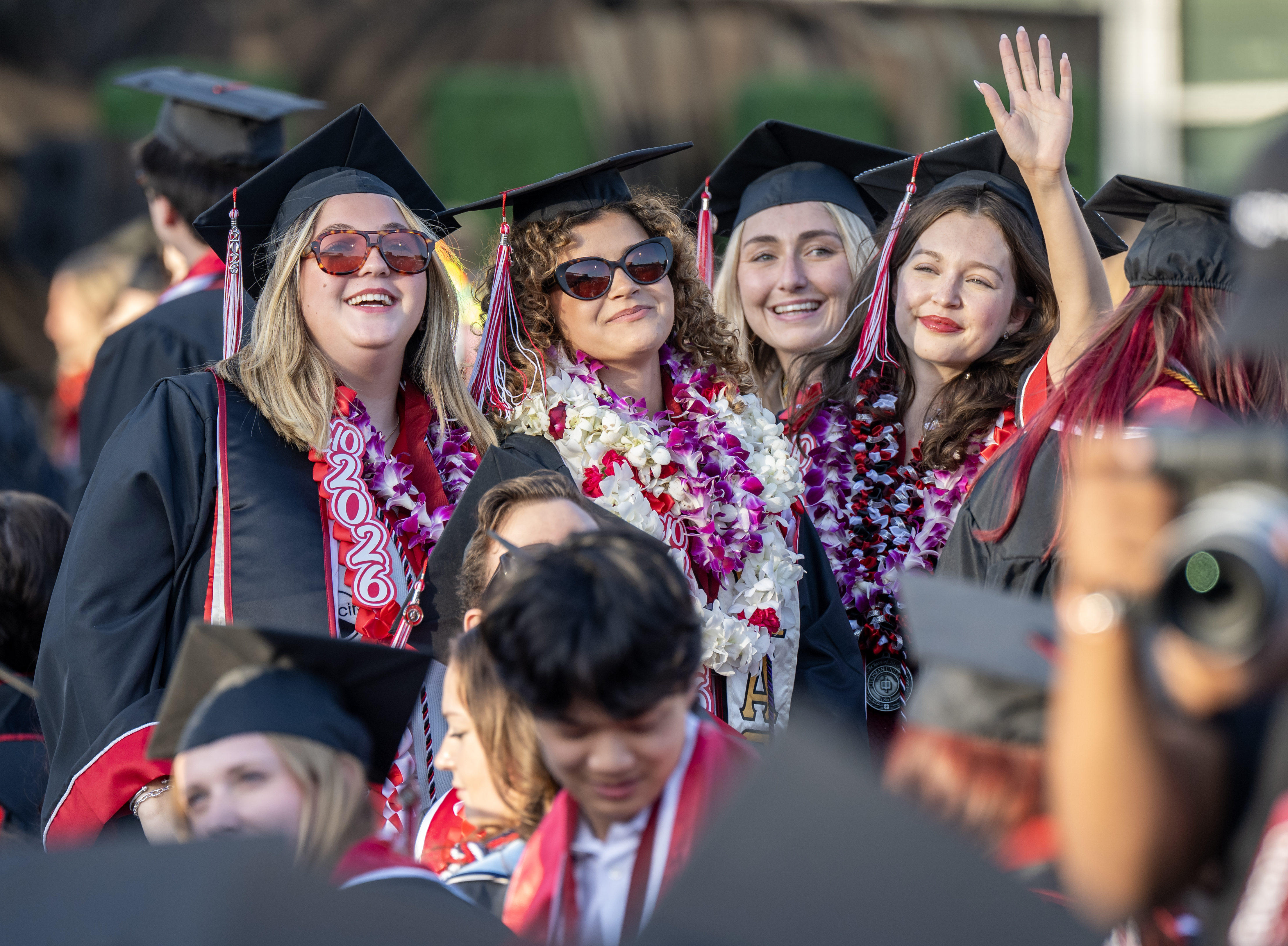 Graduates wave to their loved ones in the stands as...