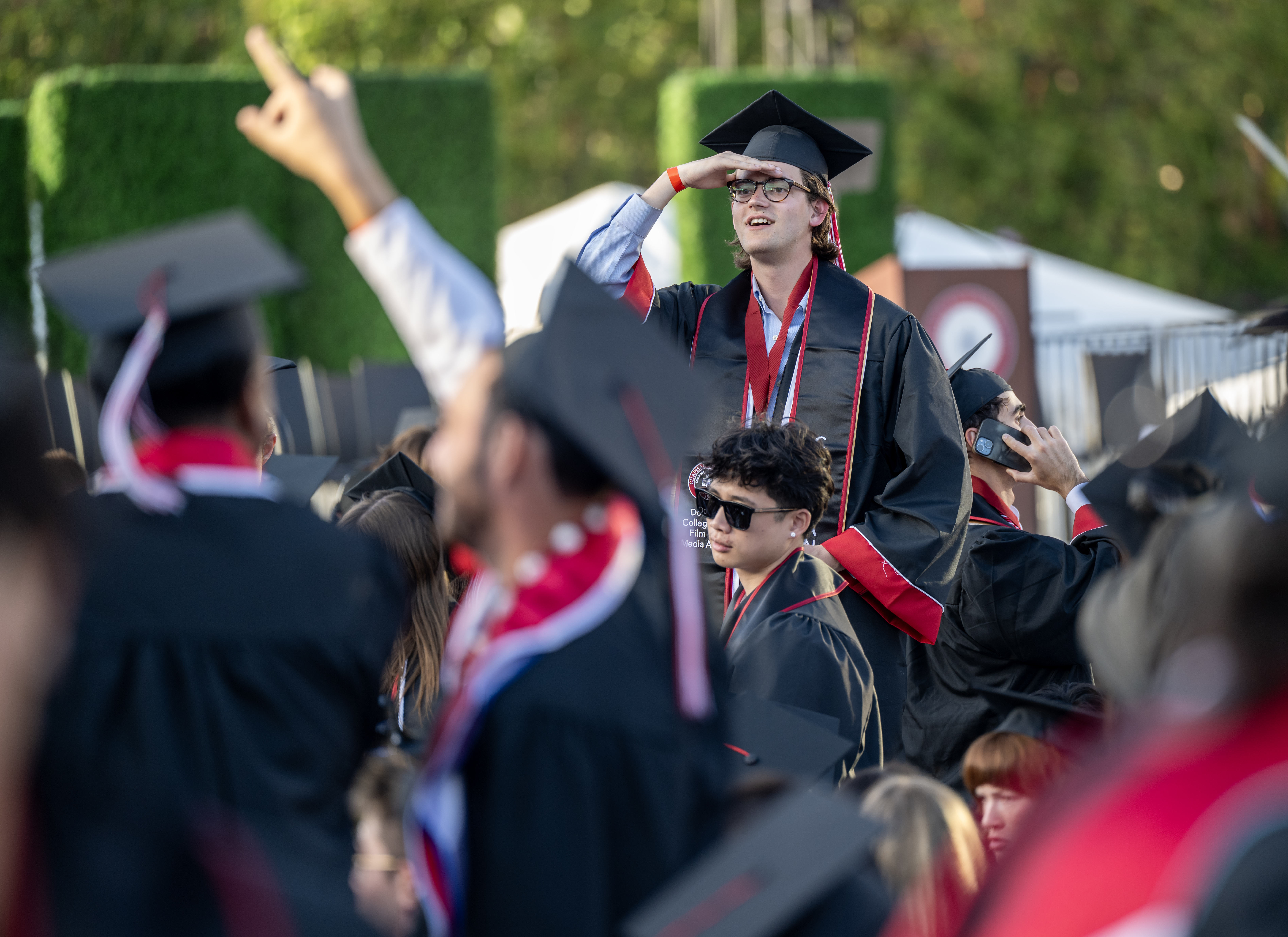 Graduates look for their loved ones in the stands as...