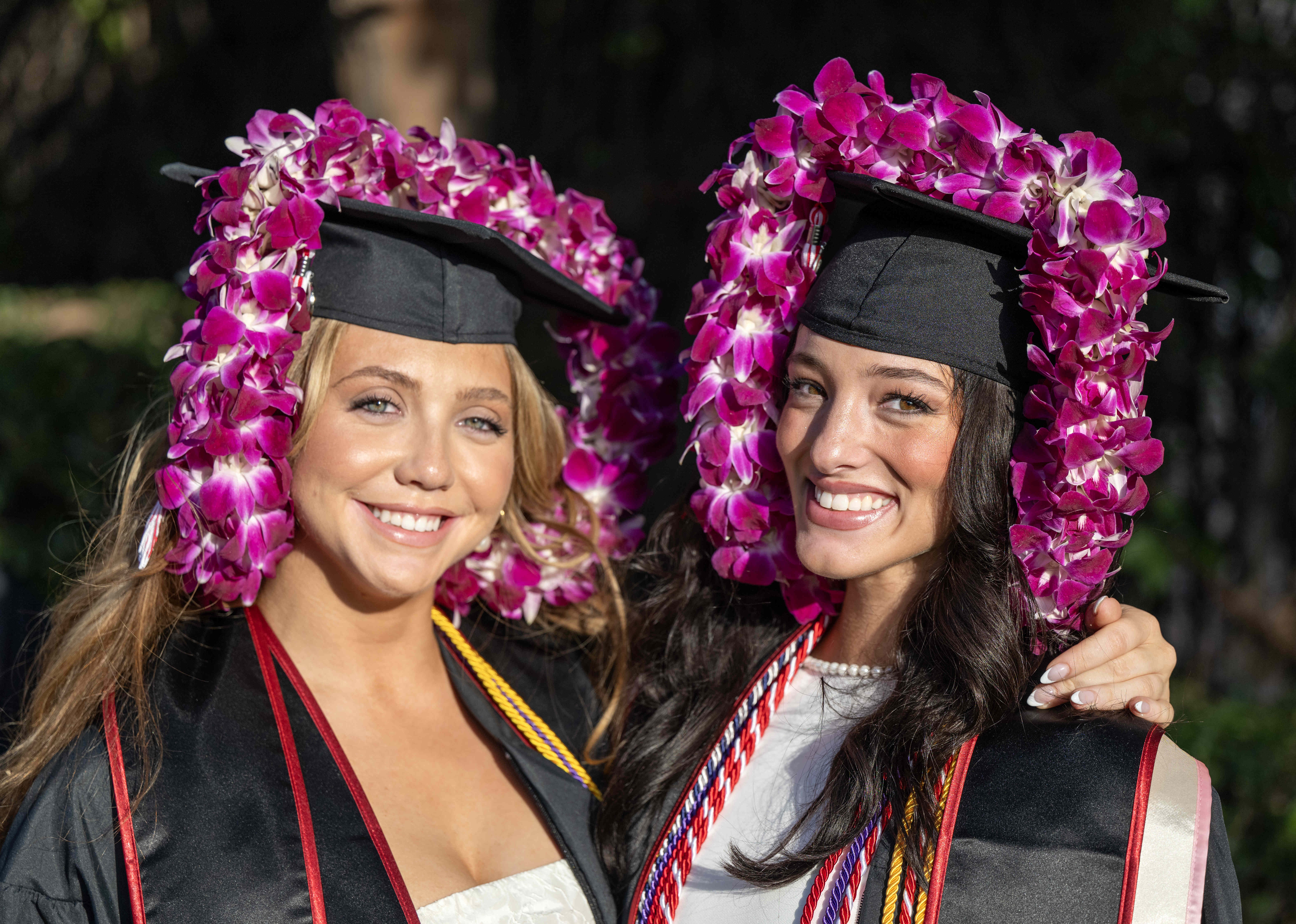 Friends Abbey Werner, left, and Braylan Enscoe jokingly wear leis...