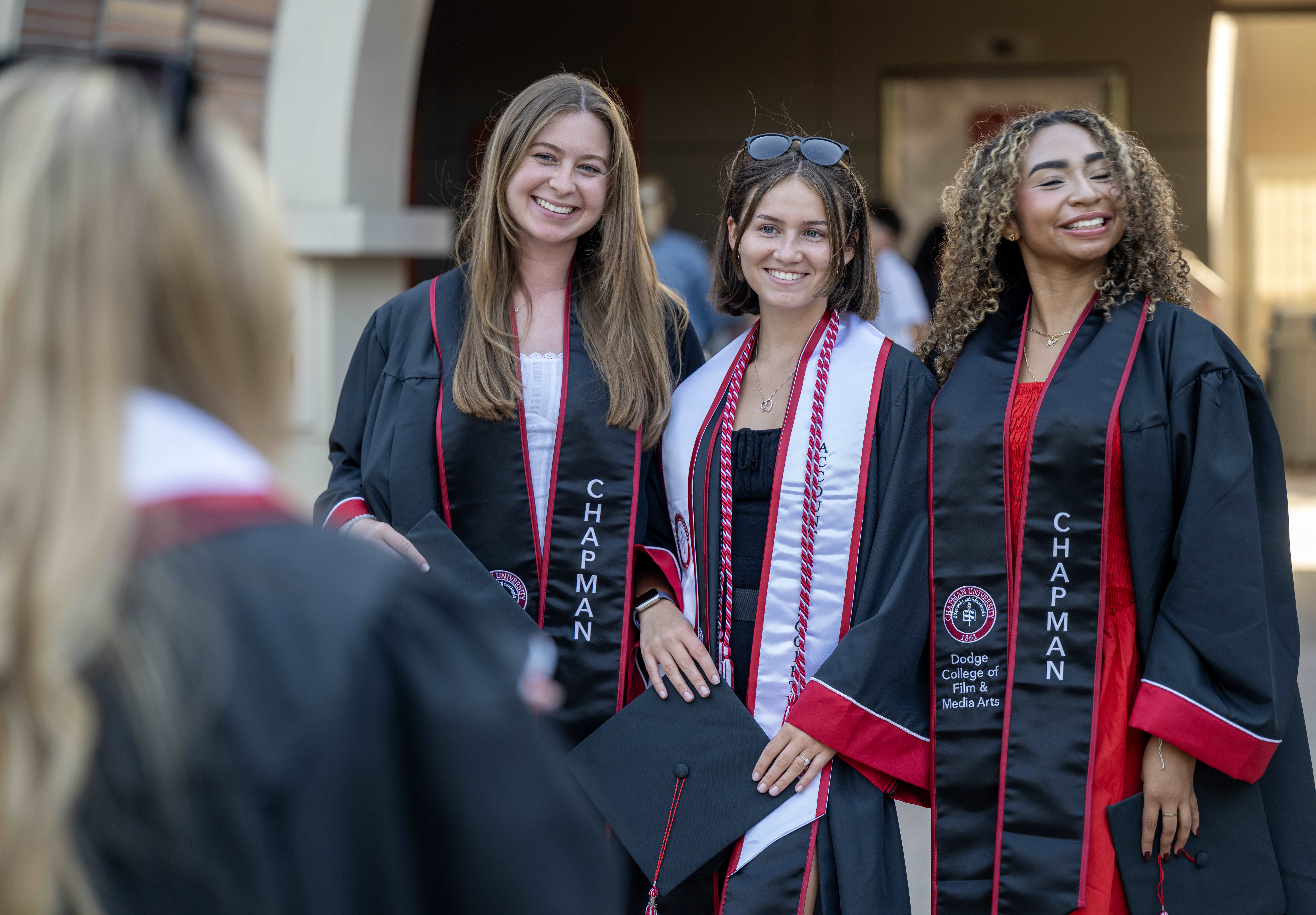 Friends pose for photos in their graduation regalia before the...