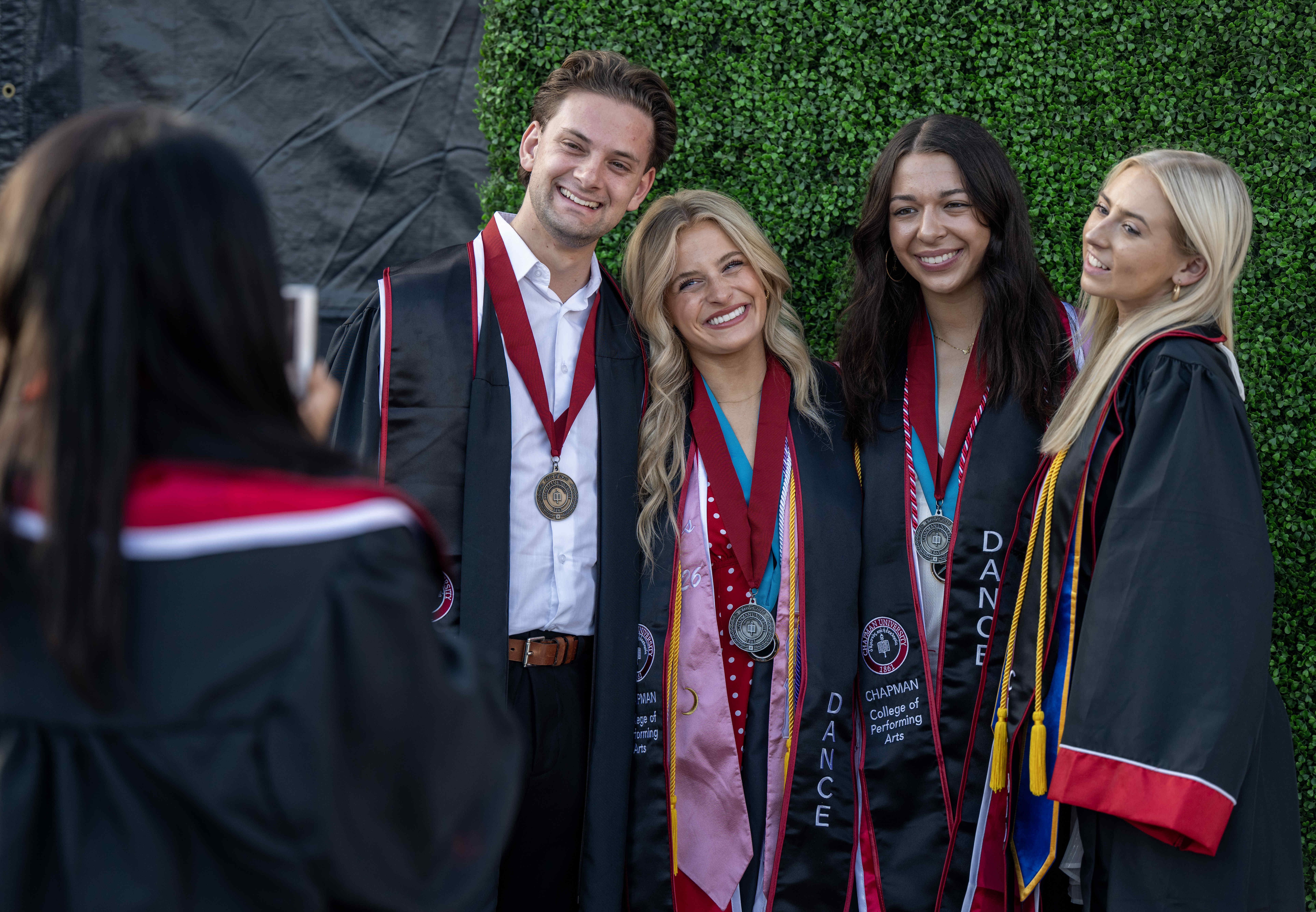 Friends pose for photos in their graduation regalia before the...