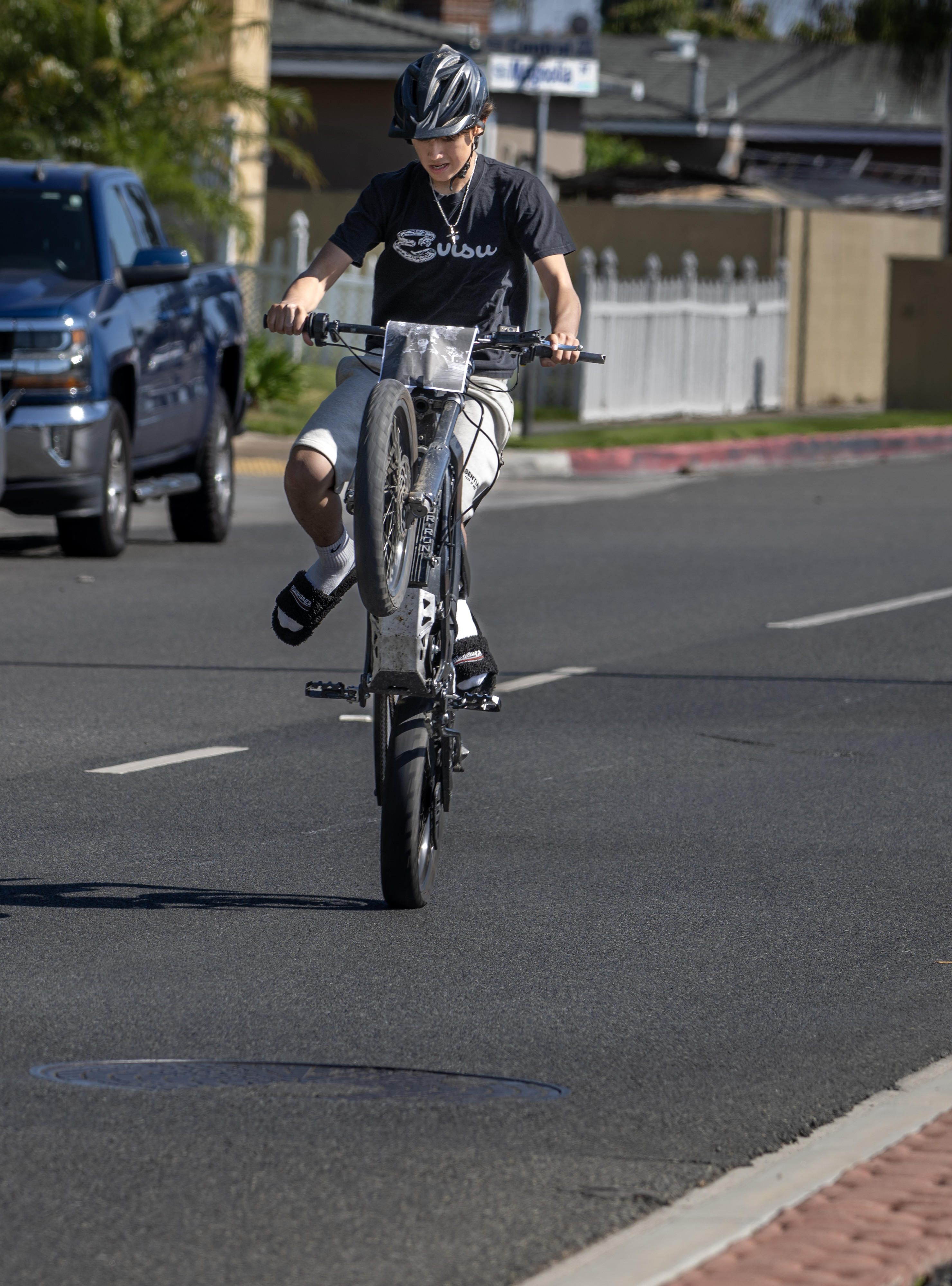 A boy pops a wheelie on his Sur-Ron e-moto bike...