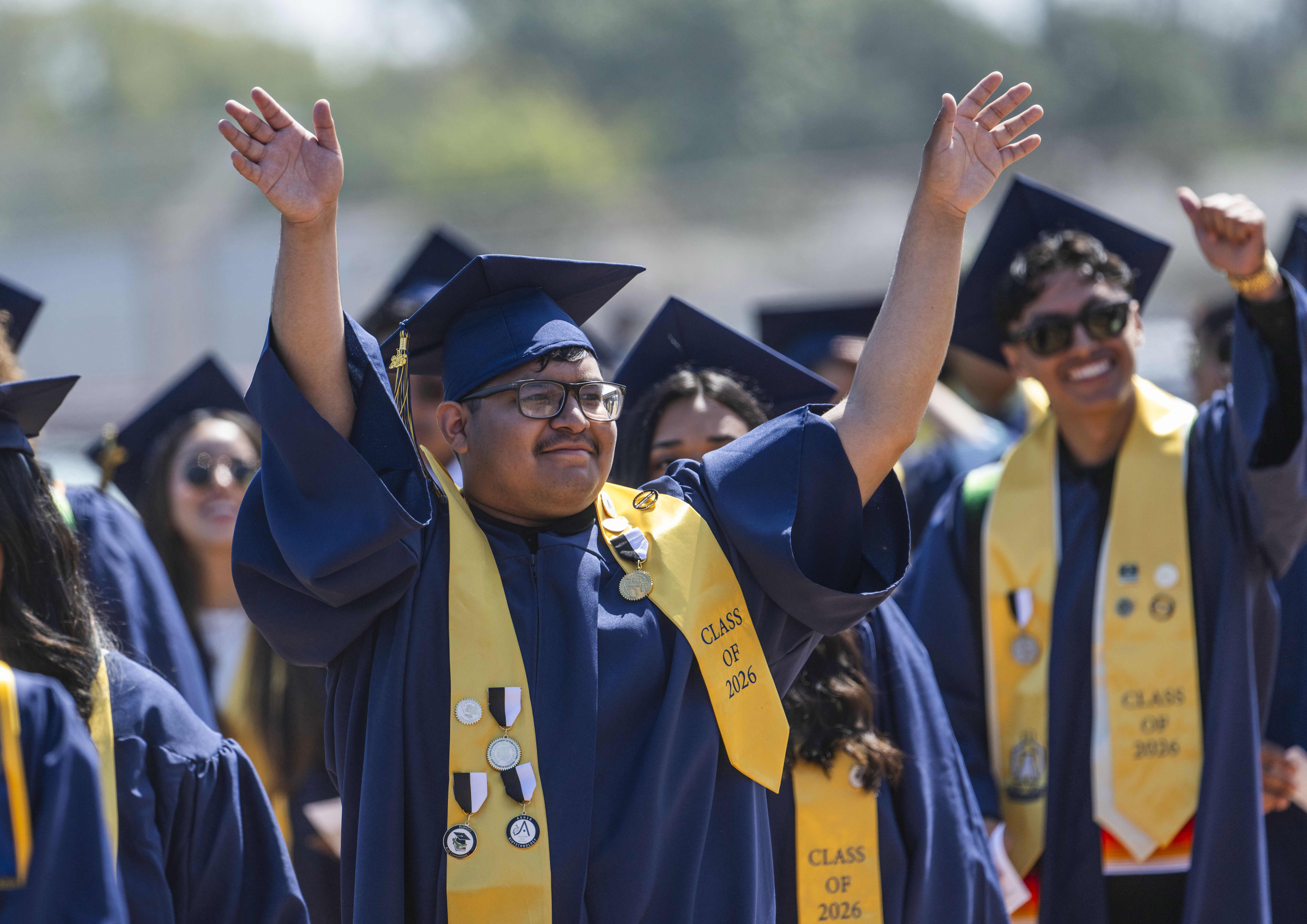 A graduating senior waves to family as he walks into...