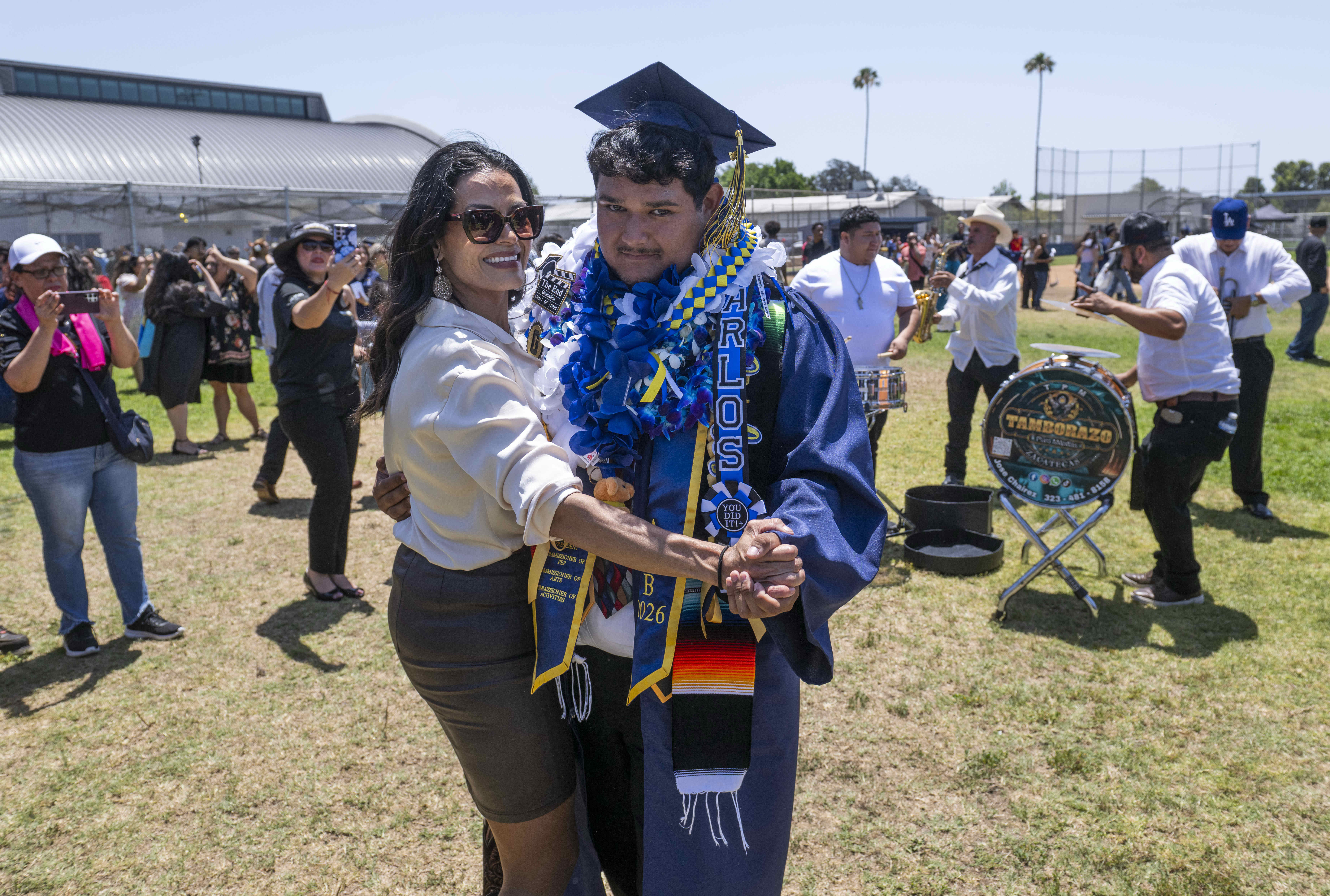 As banda group plays, graduate Carlos Ramirez dances with his...