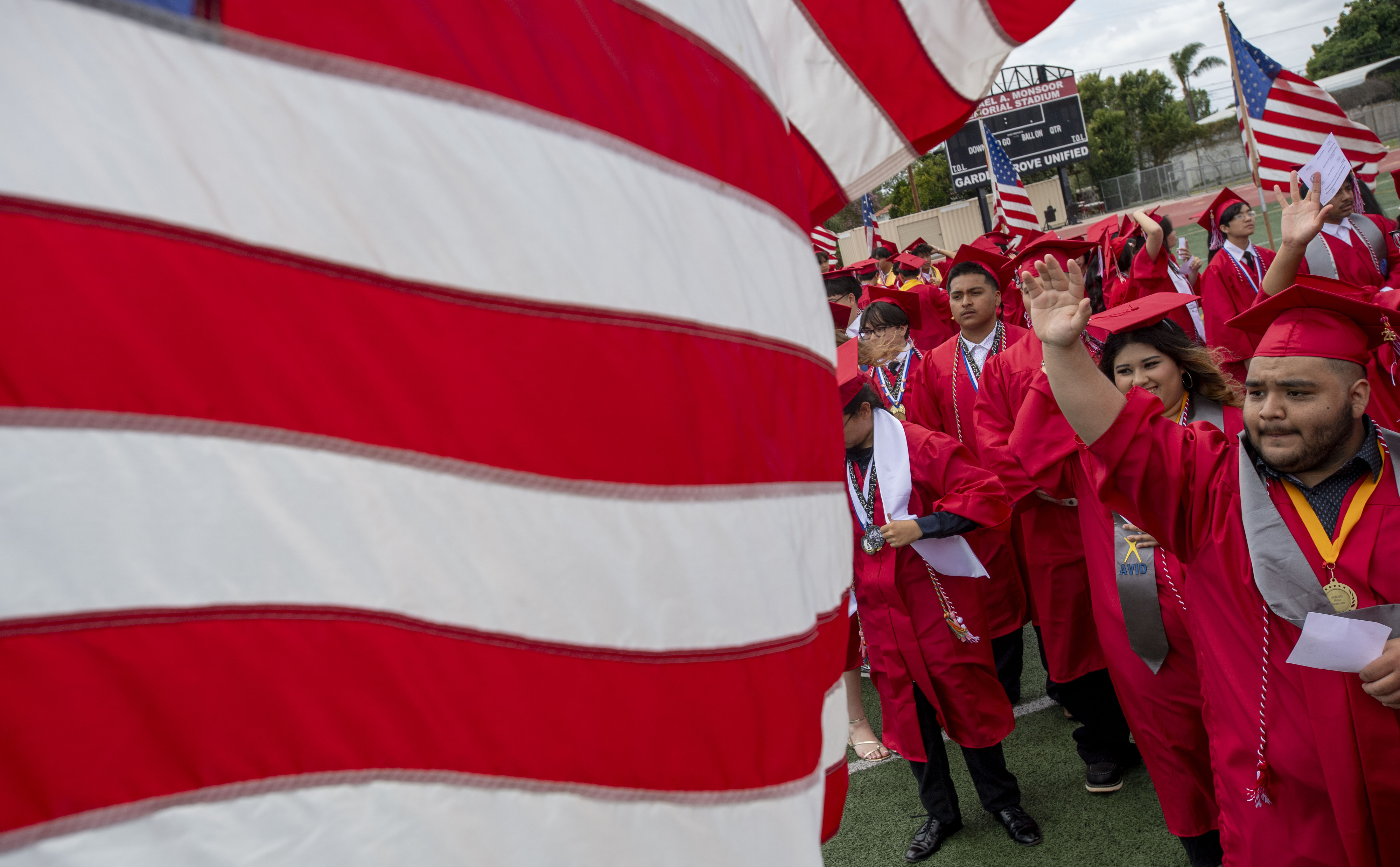 Graduates waves to the crowd as the march into the...