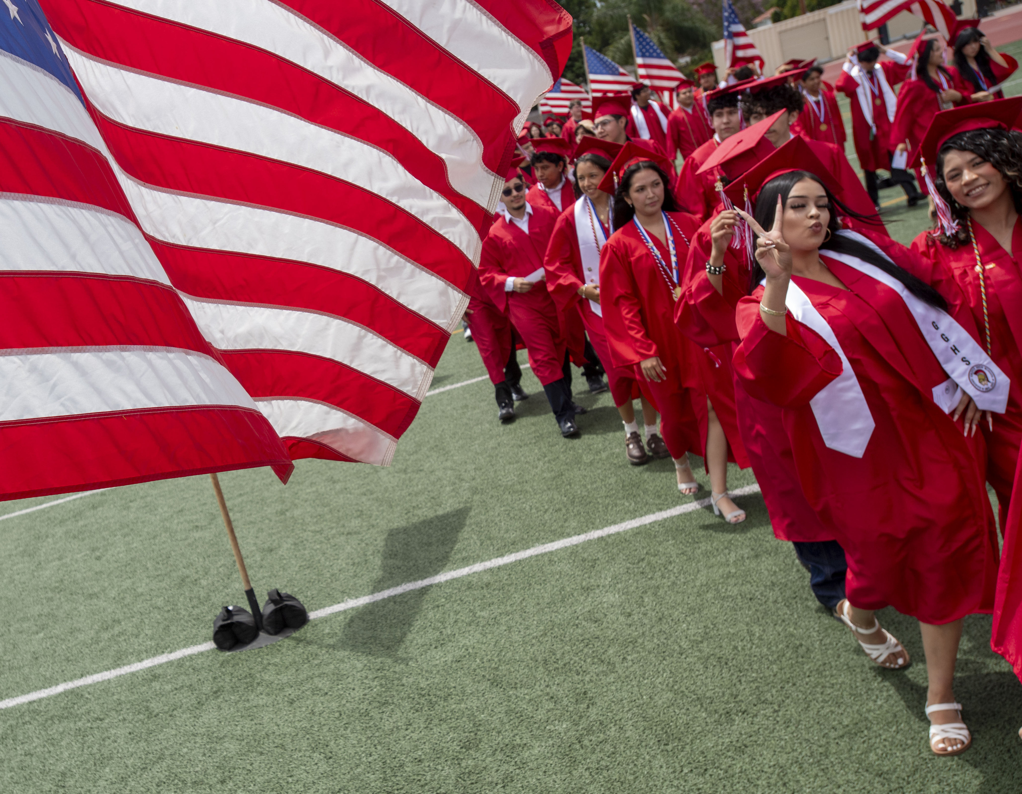 Graduates waves to the crowd as the march into the...