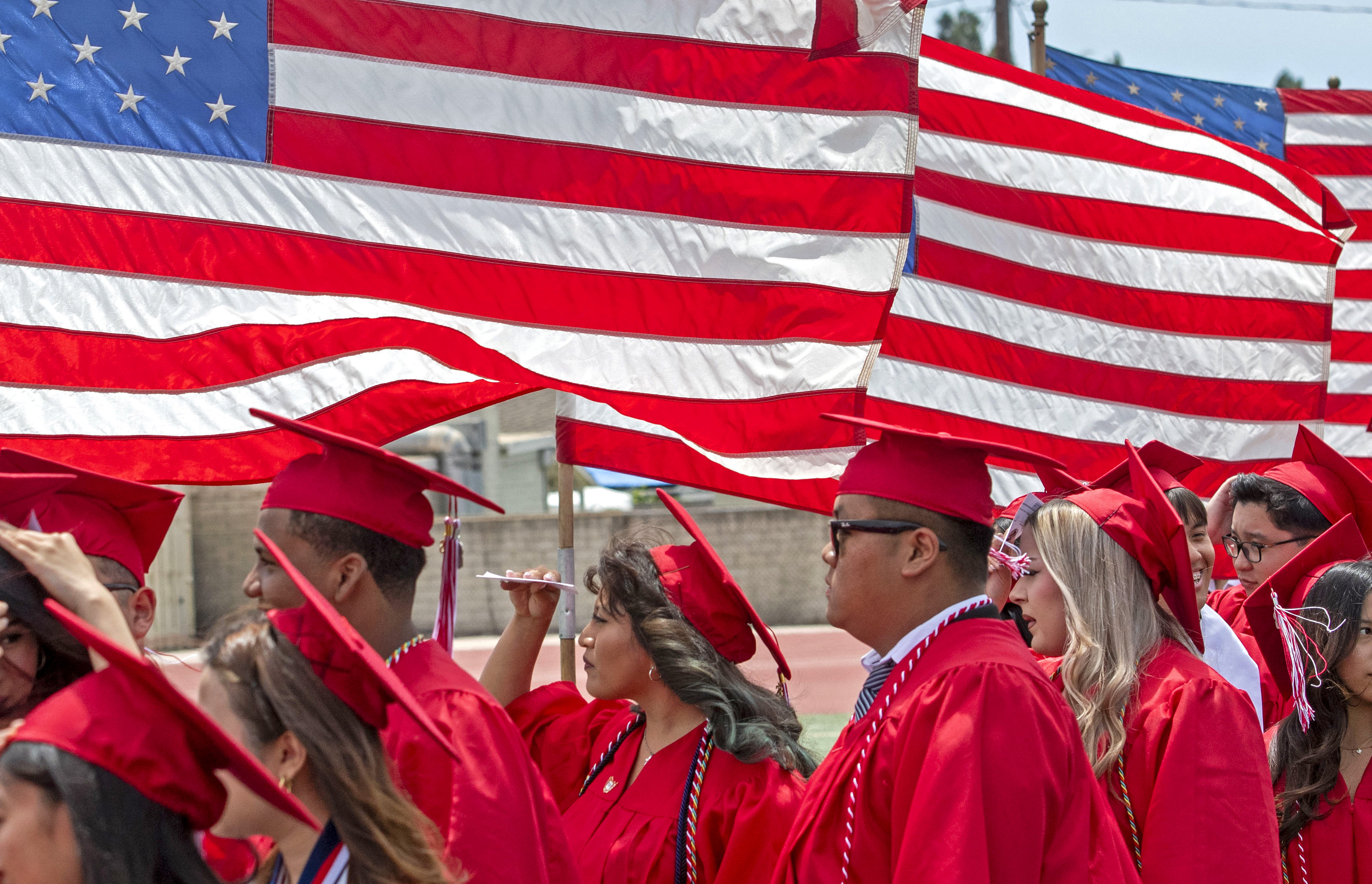 Graduates waves to the crowd as the march into the...