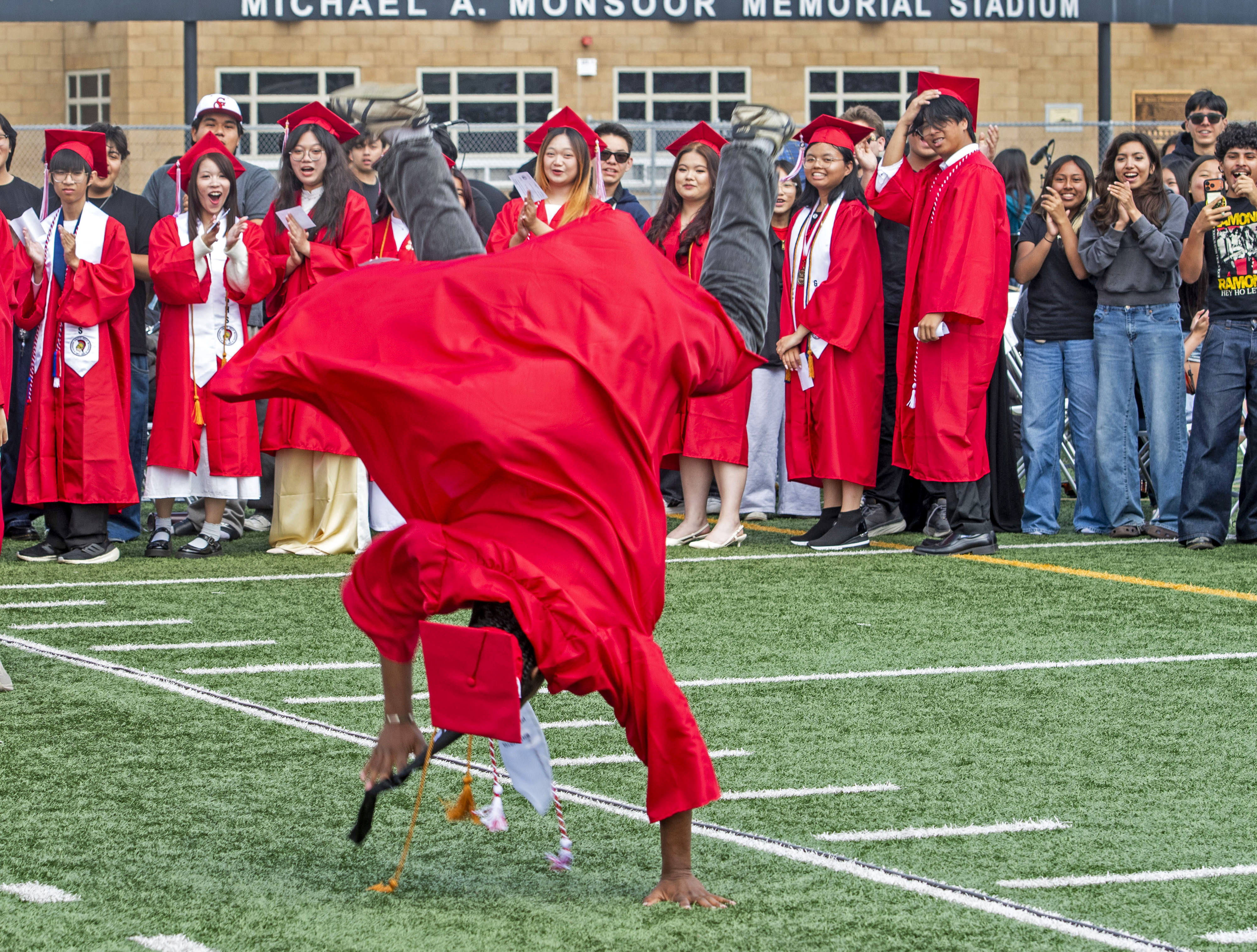 Kenji Atuatasi completes a backflip as classmates smile during the...