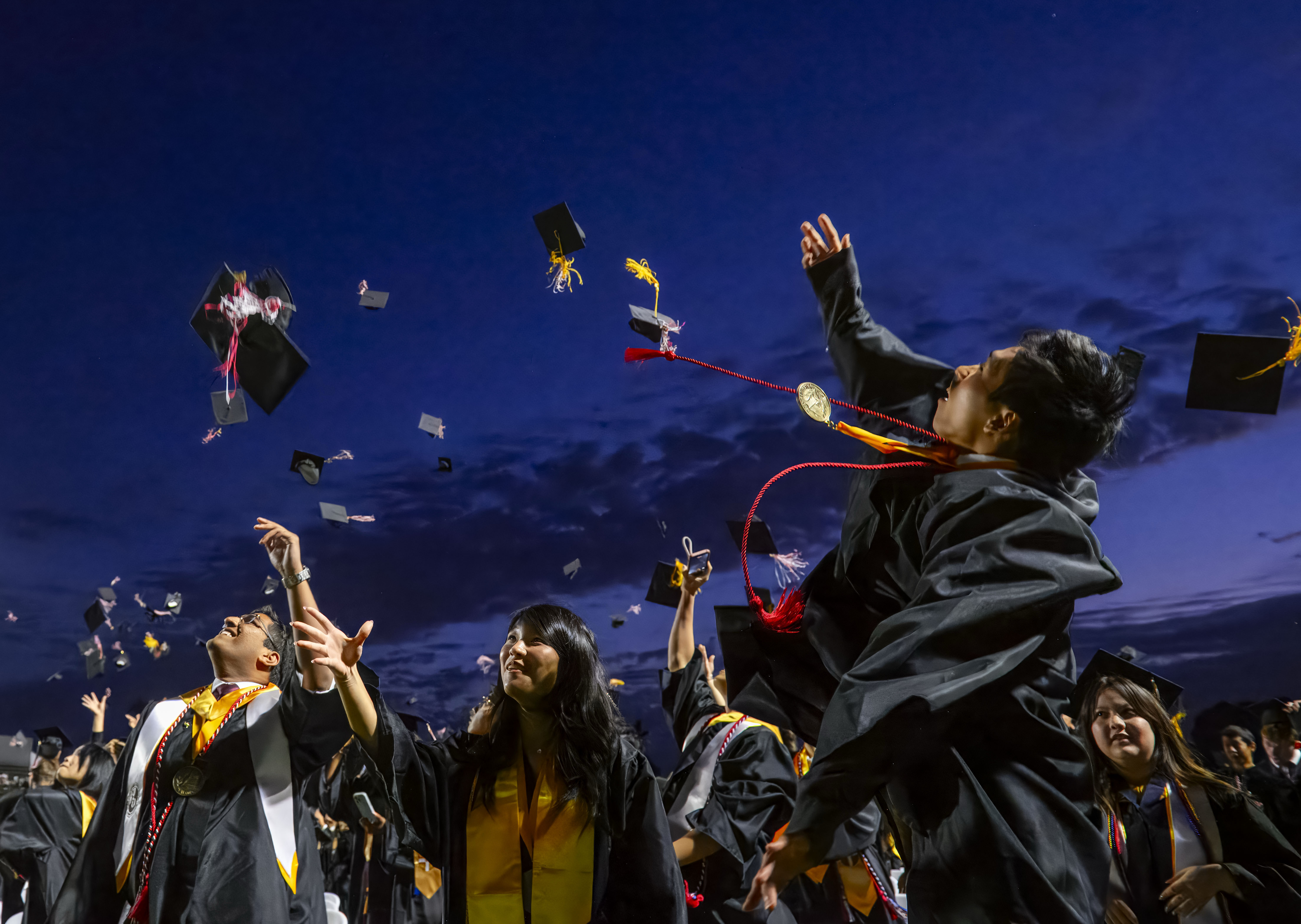 Graduates toss their caps into the air following the Troy...