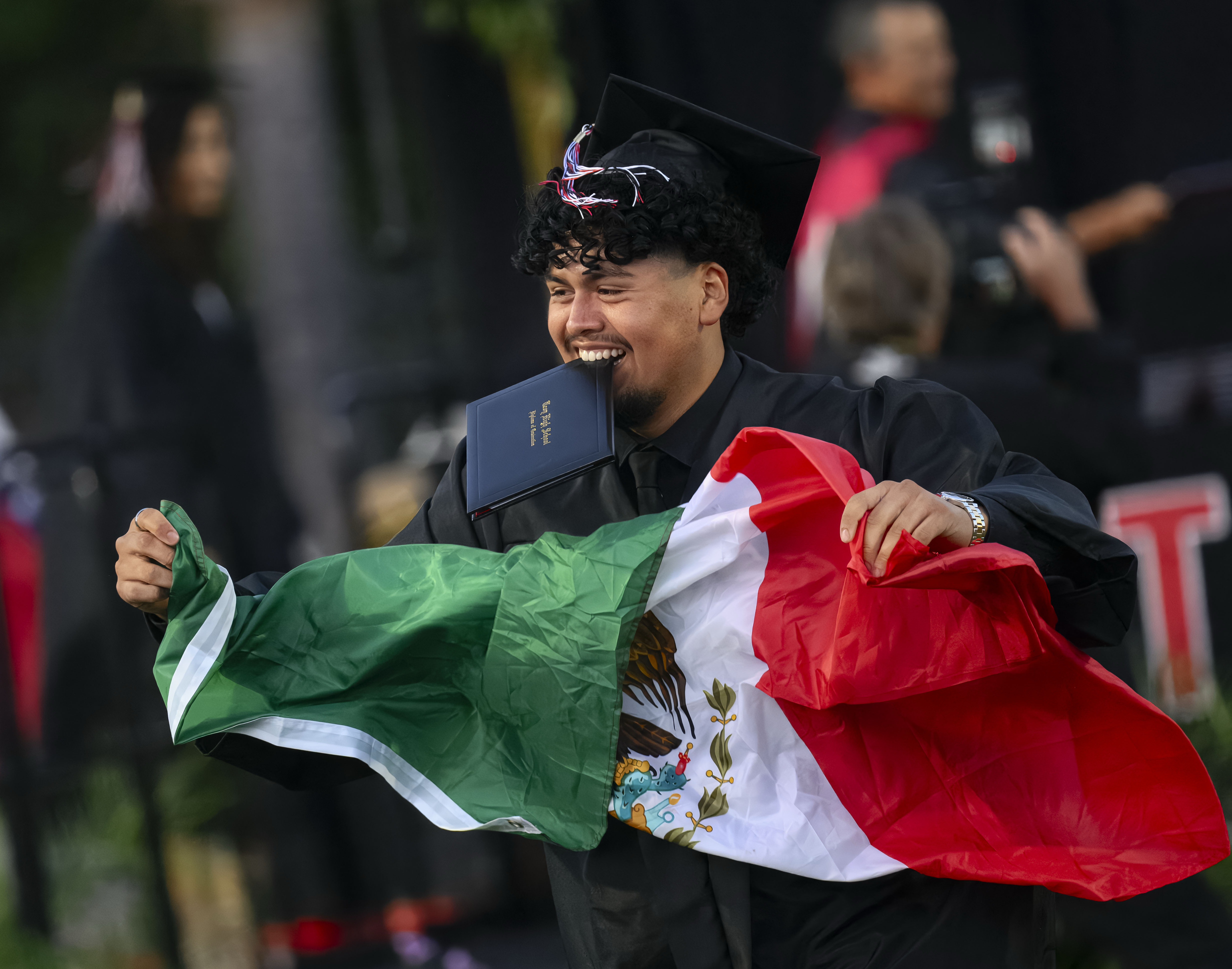 A graduate celebrates after receiving his diploma at the Troy...
