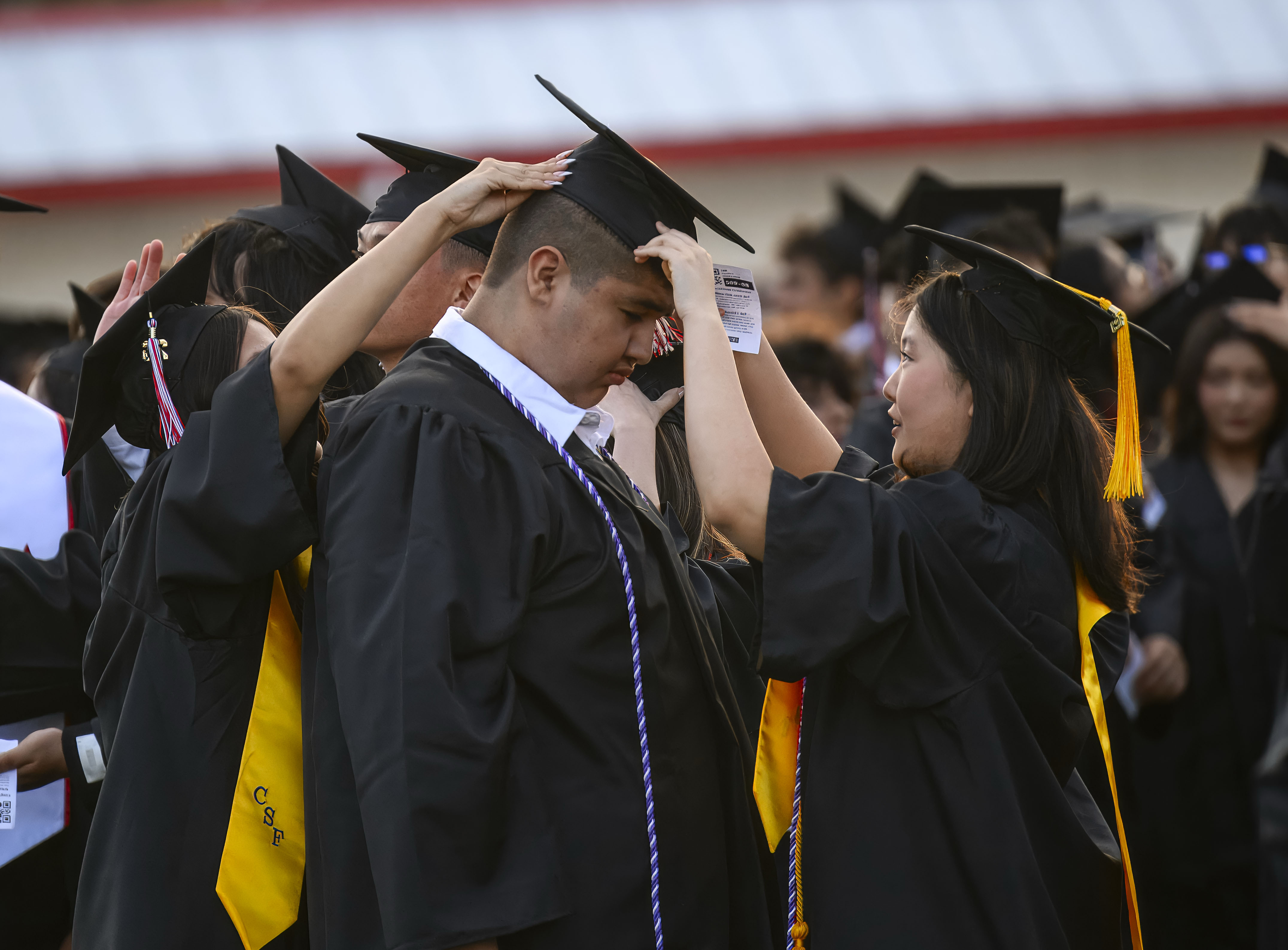Paulina Lee, right, helps adjust the cap of a fellow...