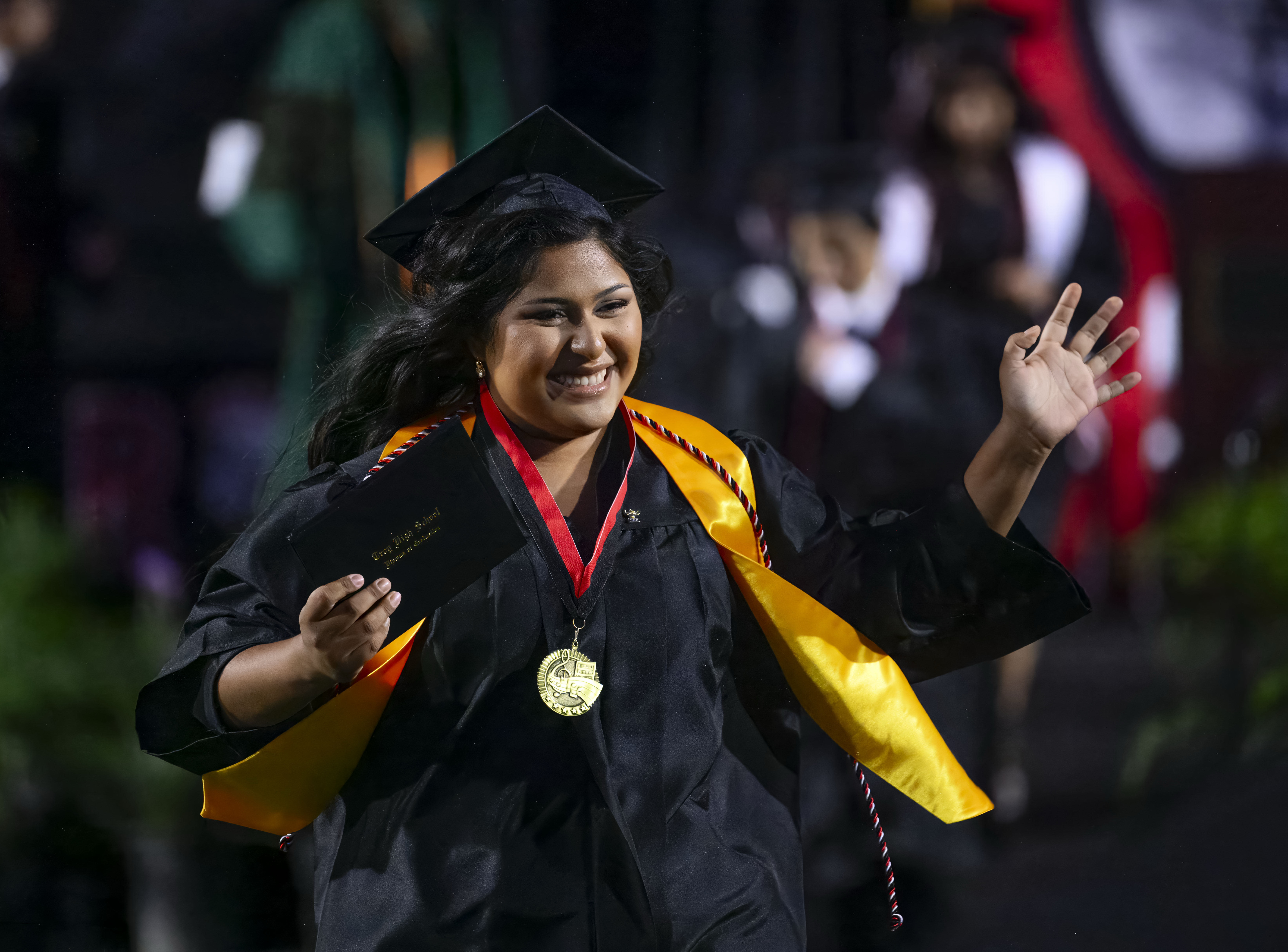 A happy graduate runs off the stage after receiving her...