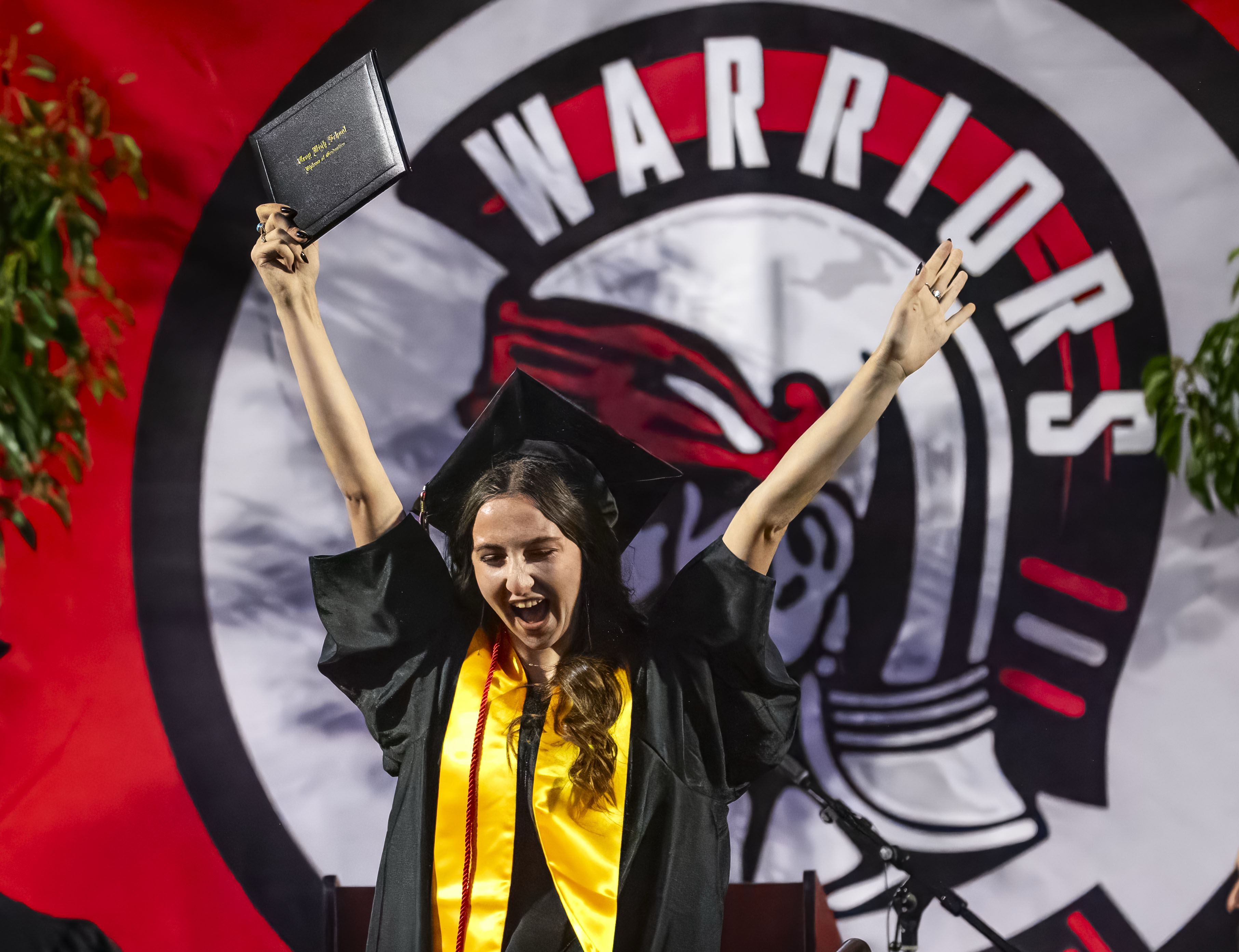 A graduate celebrates her accomplishment after receiving her diploma at...