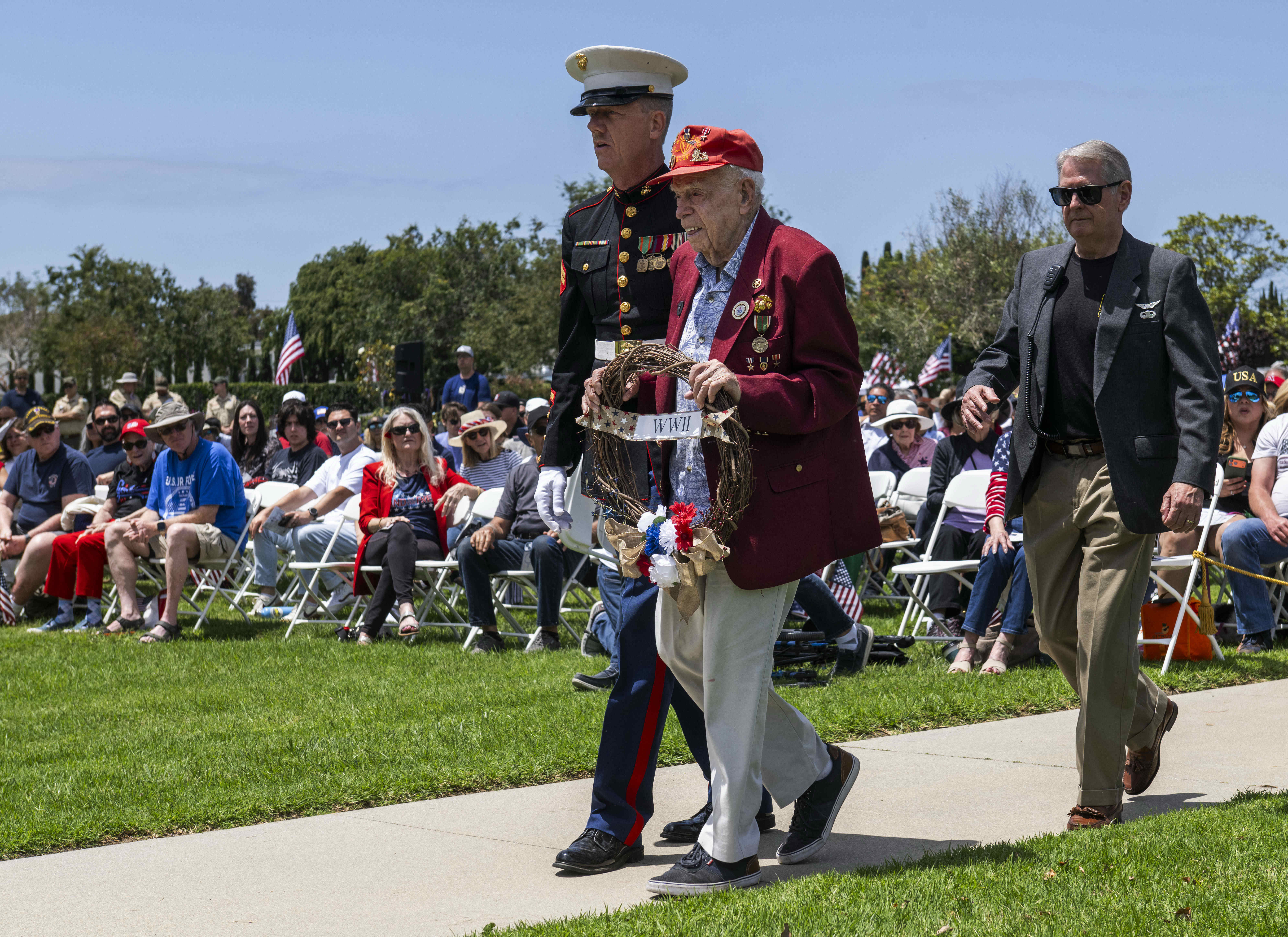 Marine Corps veteran Charles Cram, 100, center, is helped by...
