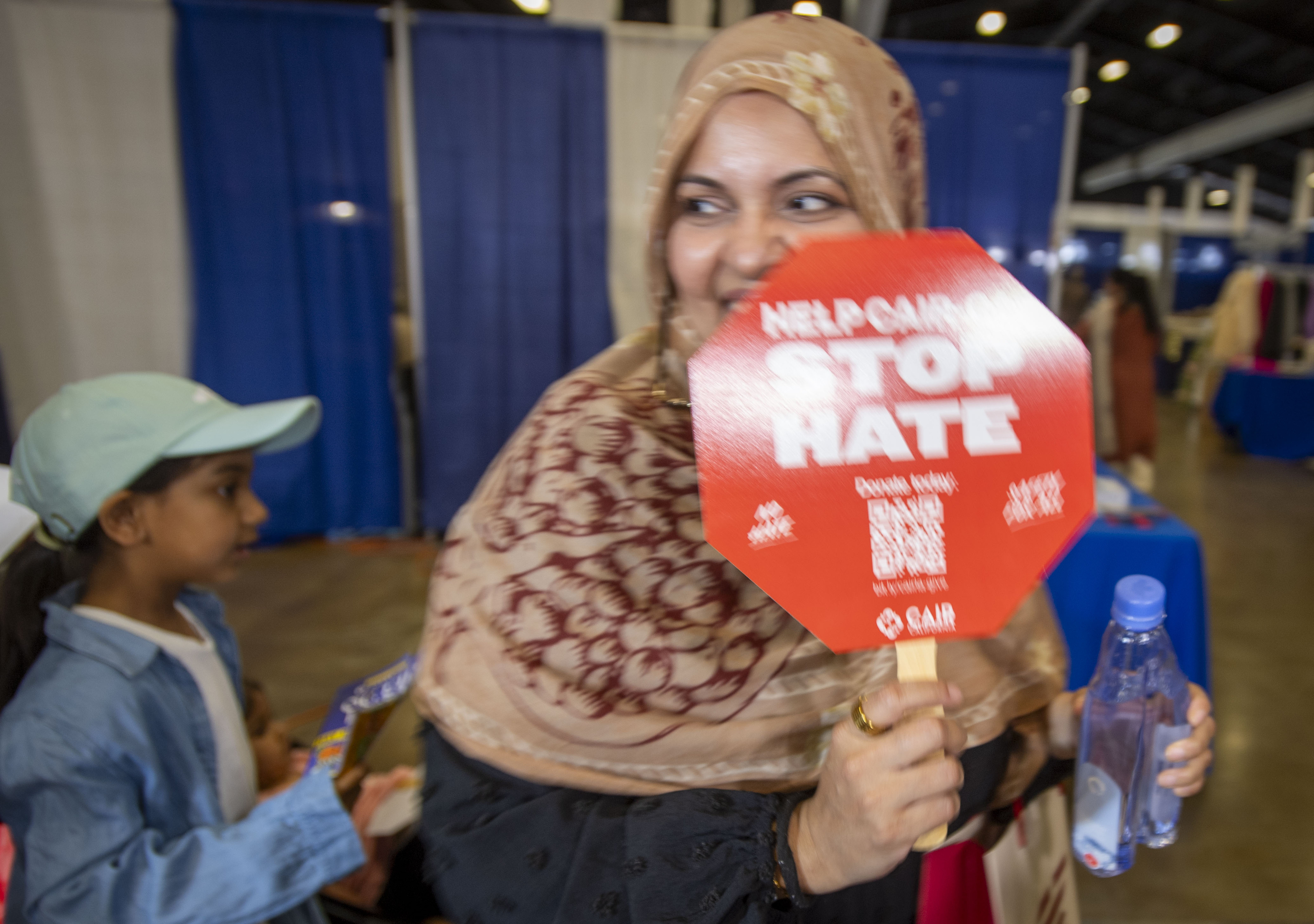 A woman carries one of the fans handed out by...