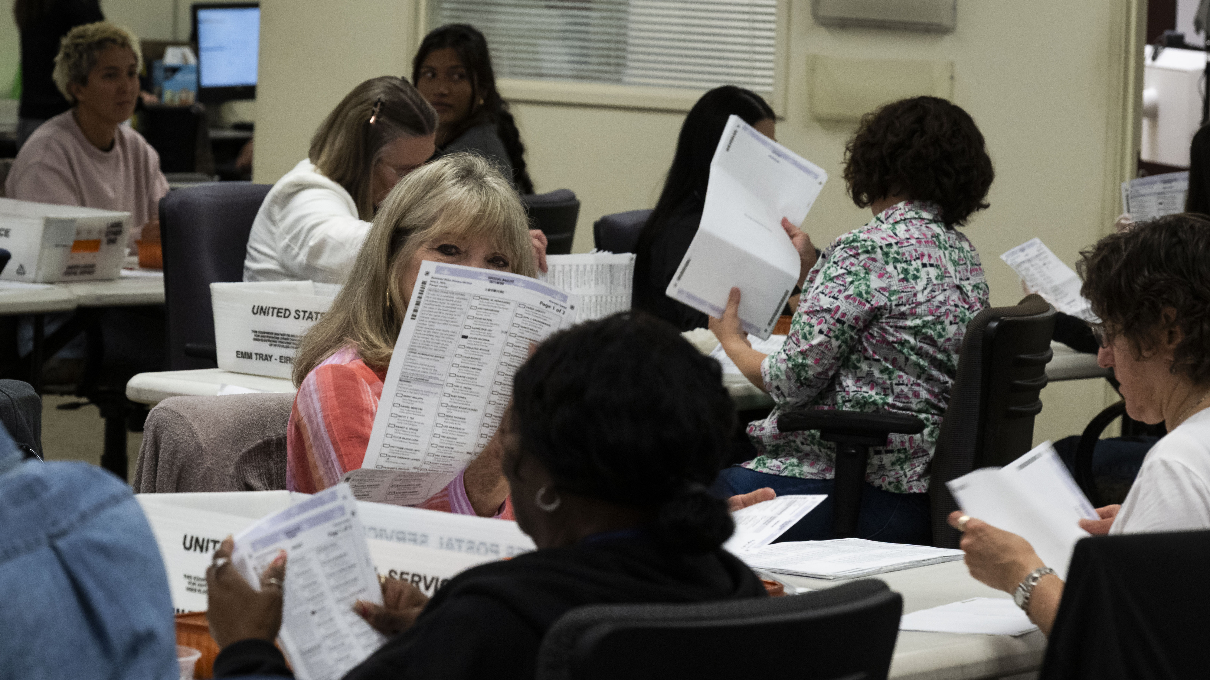 Workers take in ballots in the vote-by-mail processing area at...