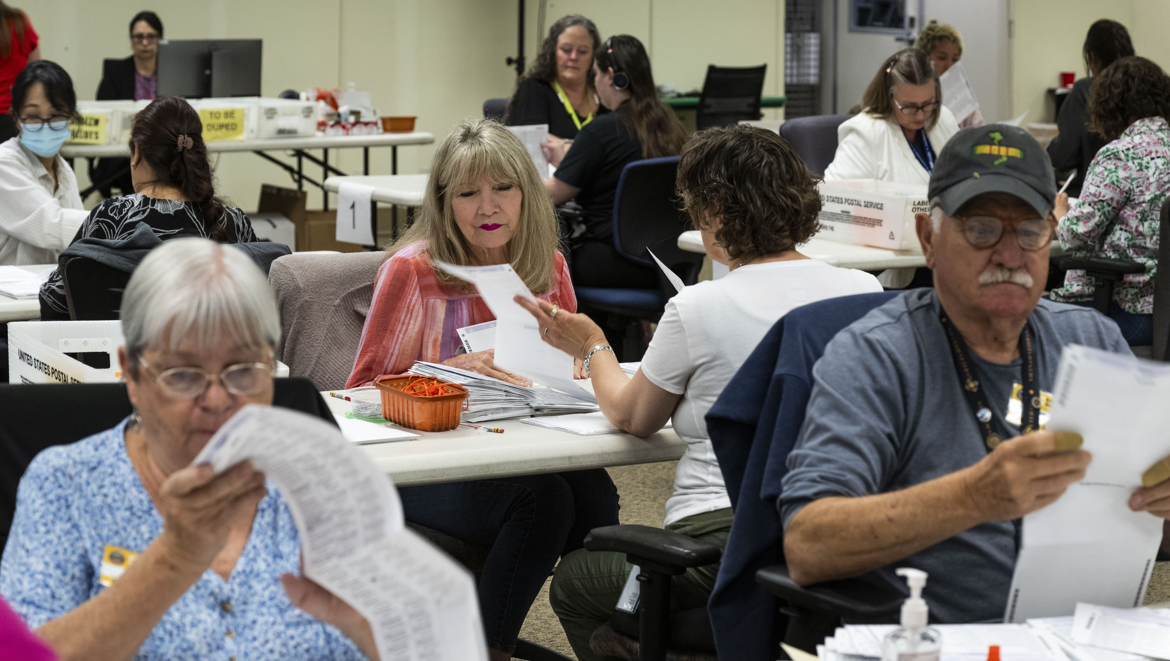 Workers take in ballots in the vote-by-mail processing area at...