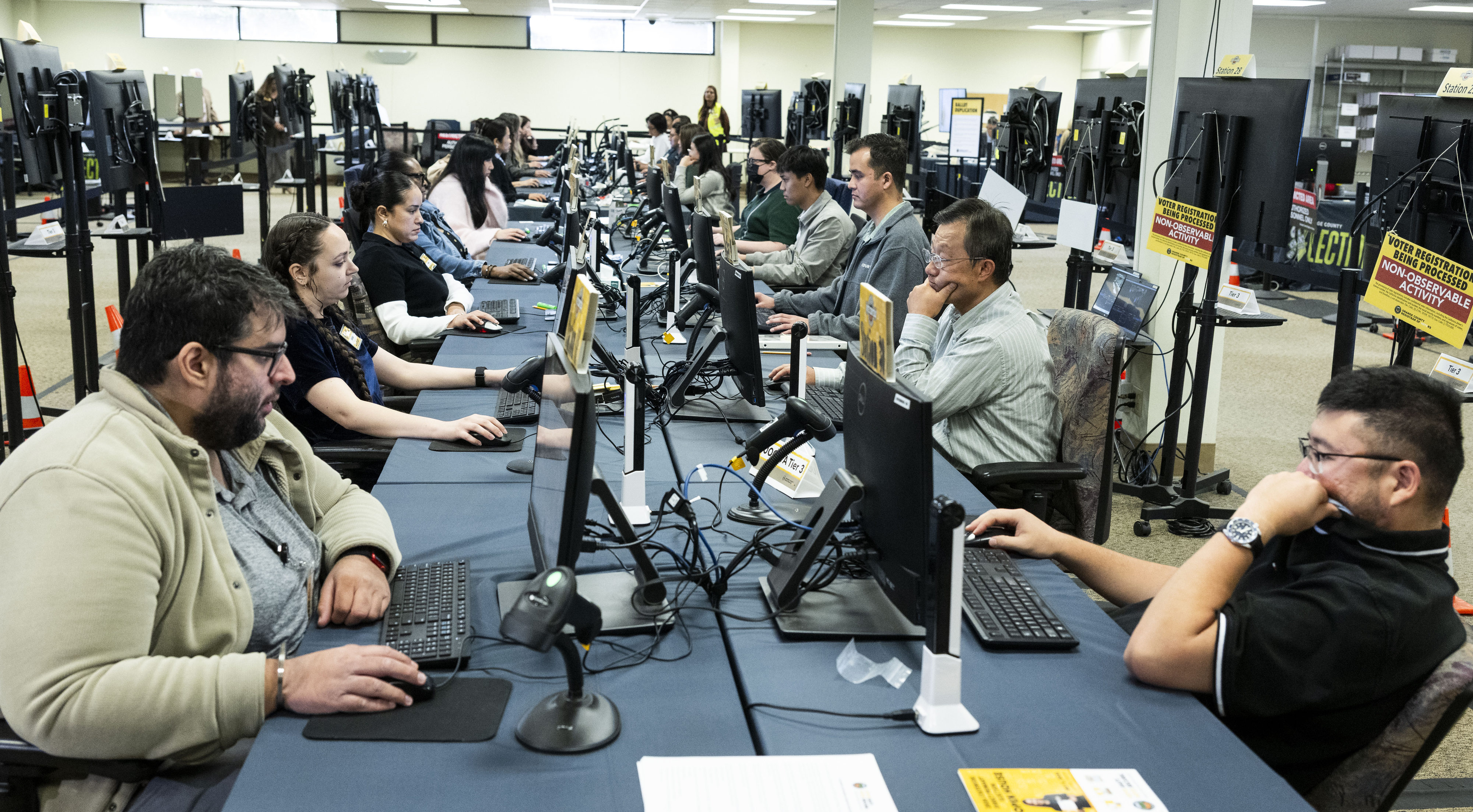 People work in signature verification at the Orange County Registrar...