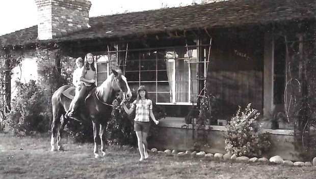 Sherry Harmon-Urena is shown in a family photo holding a horse while her younger sisters ride on horseback. (Courtesy Sherry Harmon-Urena)