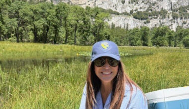 Woman holding frog next to river. CDFW photo