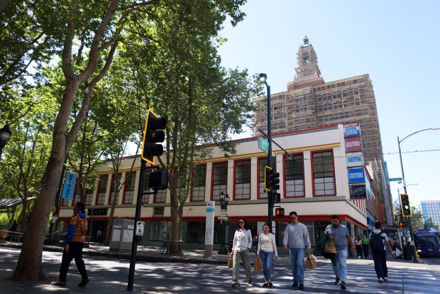 Pedestrians walk along East Santa Clara Street as the Bank of Italy building is seen in the background on Monday, April 6, 2026, in San Jose, Calif. Construction will transform former office space in the Bank of Italy building into a 109 new residential units. (Aric Crabb/Bay Area News Group)