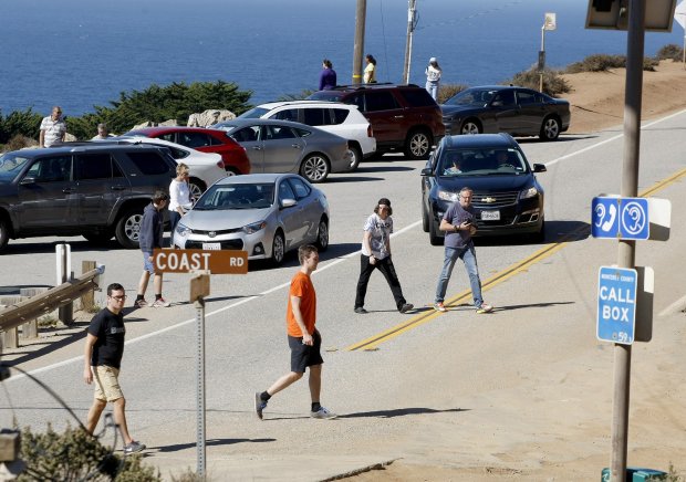 People cross Highway 1 to their cars parked on Coast Road near Bixby Creek Bridge in this Oct. 2015 photo. (Vern Fisher/Monterey Herald)