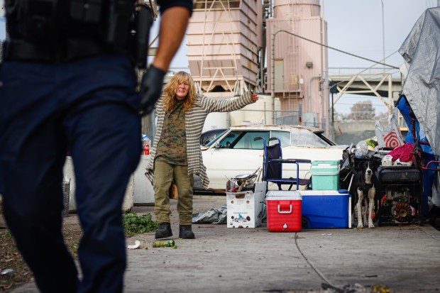 Laura Eldridge, 61, raises her arms in exasperation while a San Jose Police officer over sees the towing of the trailer she lives in as the city continues to clear homeless encampments in San Jose, Calif., on Wednesday, Dec. 10, 2025. (Shae Hammond/Bay Area News Group)