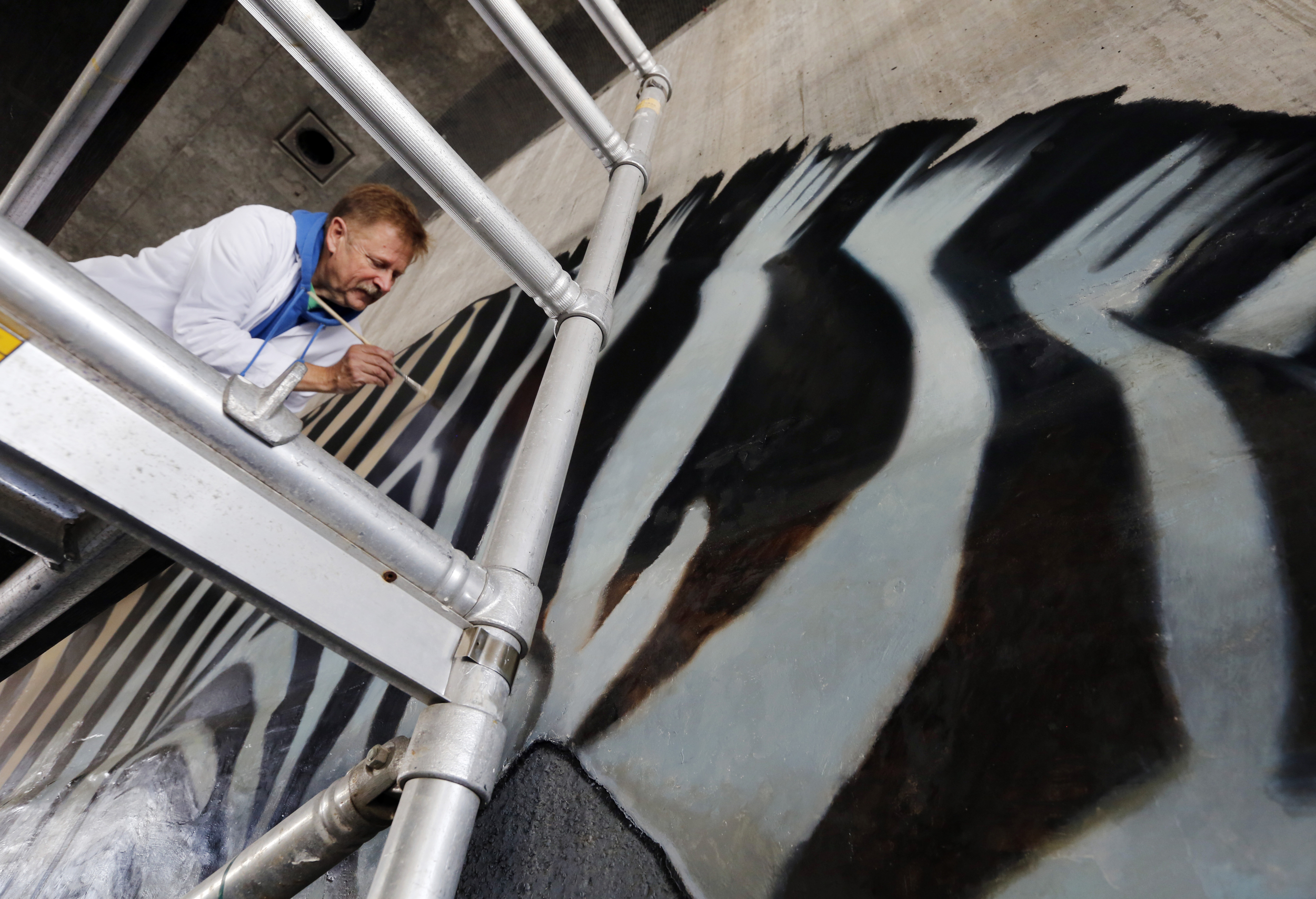 Dan Fontes paints on a scaffolding under Interstate 580 on...