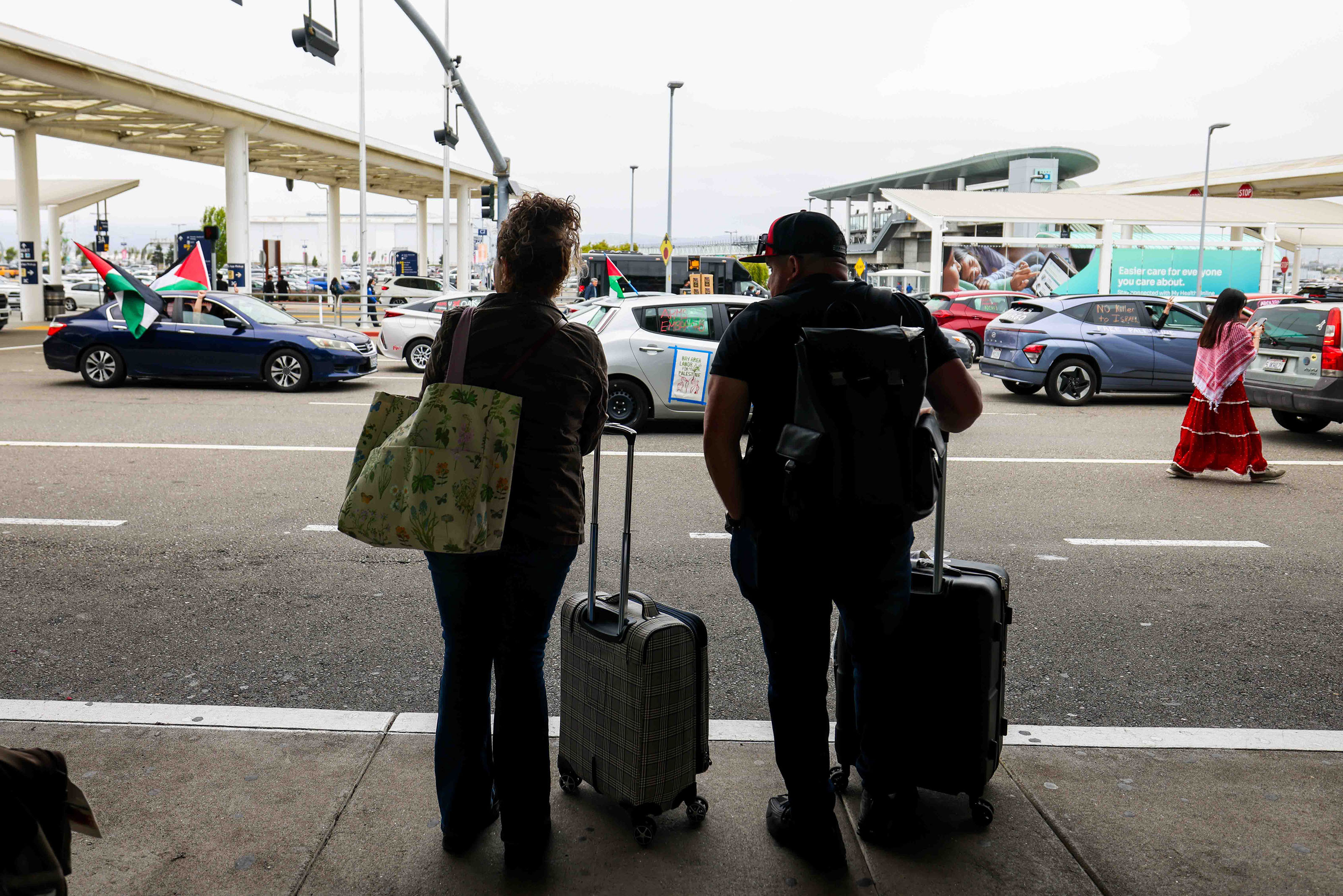 Passengers wait for their ride as demonstrators in a caravan...