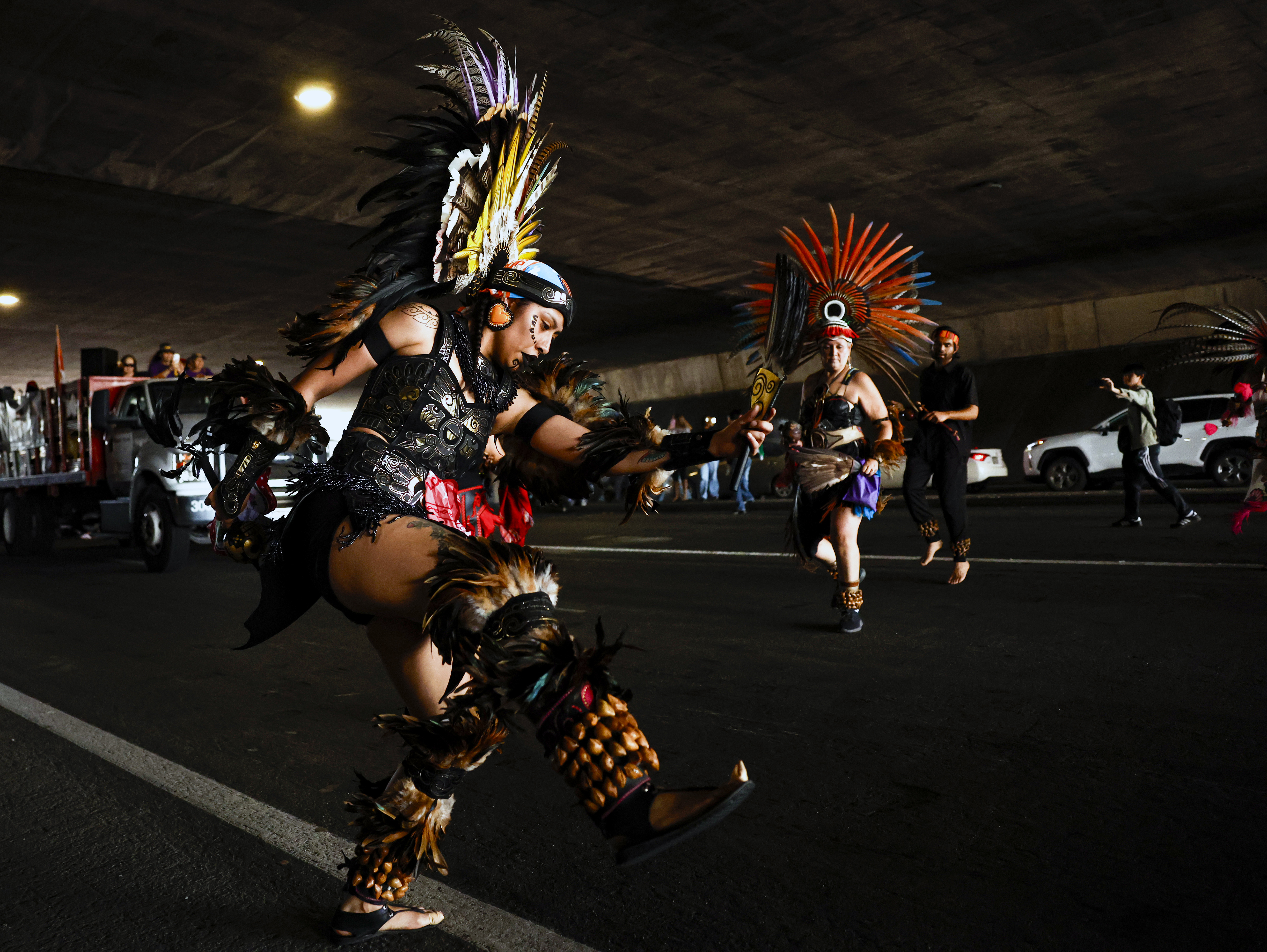 Aztec dancers participate in a May Day protest under Interstate...