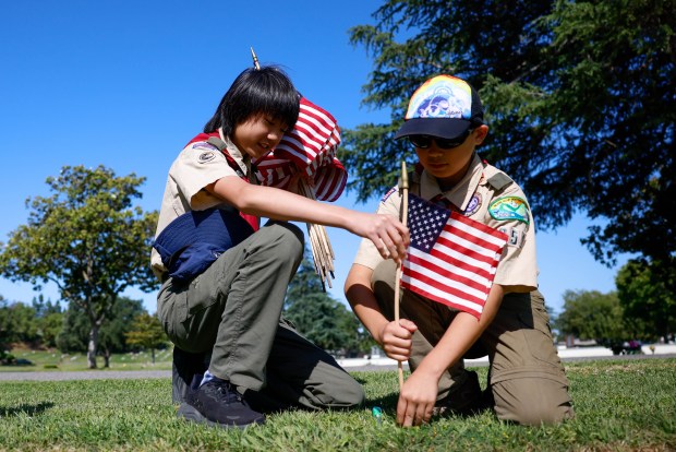 Boy Scouts Zachary Hwang, 13, of San Jose, left, and Aidan Wu, 13, of San Jose, place flags at the gravesites of people who served in the US Arm Forces at Oak Hill Cemetary in San Jose, Calif., on Saturday, May 23, 2026. (Shae Hammond/Bay Area News Group)