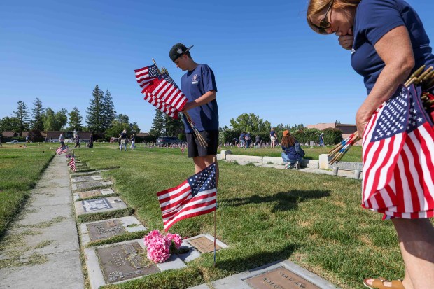 Casen Hansen, 13, and his mother, Bonnie Hansen, place American flags on the gravestones of fallen soldiers for Memorial Day weekend at Memory Garden Cemetery in Livermore, Calif., Saturday, May 23, 2026. About 120 mother-and-son teams from the Livermore chapter of the Young Men's Service League, in partnership with members of American Legion Post 47, took part in the annual event at Memory Garden Cemetery and St. Michael's Cemetery. (Ray Chavez/Bay Area News Group)