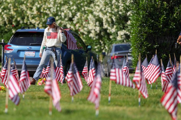 A volunteer places American flags on the gravestones of fallen soldiers for Memorial Day weekend at Memory Garden Cemetery in Livermore, Calif., Saturday, May 23, 2026. About 120 mother-and-son teams from the Livermore chapter of the Young Men's Service League, in partnership with members of American Legion Post 47, took part in the annual event at Memory Garden Cemetery and St. Michael's Cemetery. (Ray Chavez/Bay Area News Group)