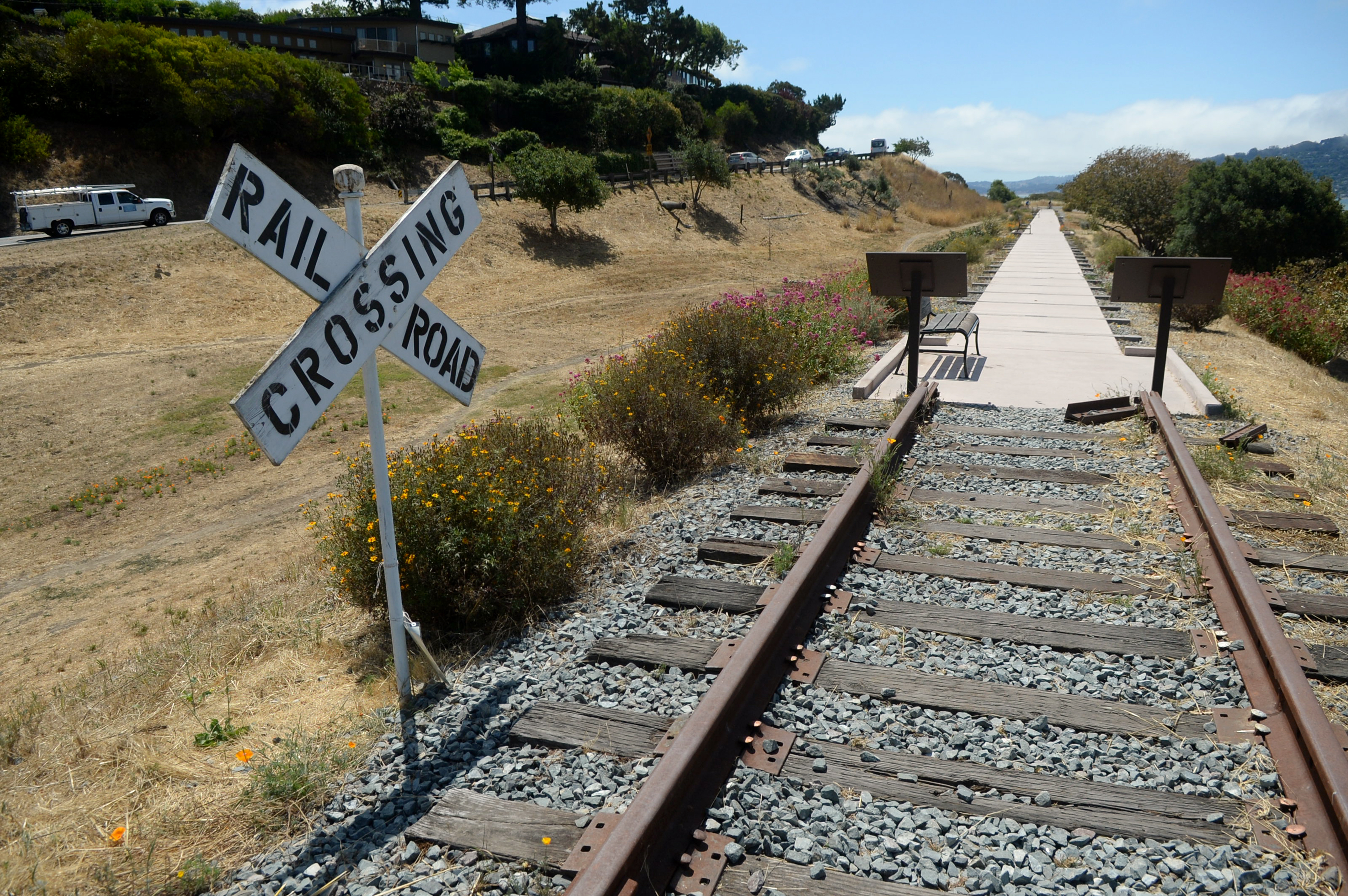A railroad crossing sign stands next to the Old Rail...