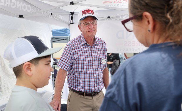 While campaigning at the Escondido Street Fair, San Diego County Supervisor Jim Desmond listens to Victoria Baay, right, here with son Nolan Baay, 9, both of Borrego Springs, on Sunday, May 17, 2026. Baay is the principal of Borrego Springs High. (John Gastaldo for The San Diego Union-Tribune)