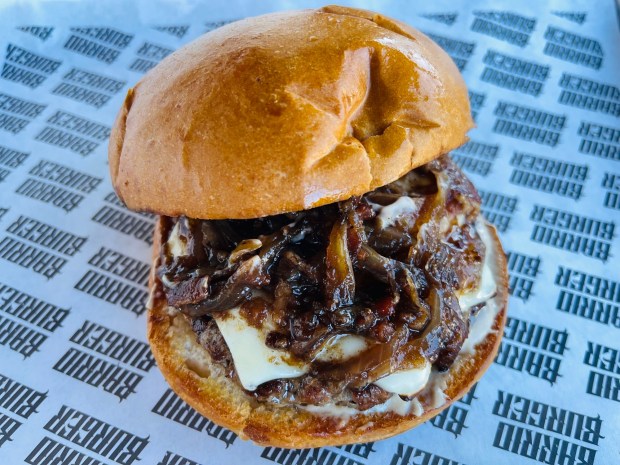 The Barrio Burger Especial is filled with caramelized onions, bacon jam, melted white cheddar cheese and angus beef patty on toasted bun. (Carlos Rico / The San Diego Union-Tribune)