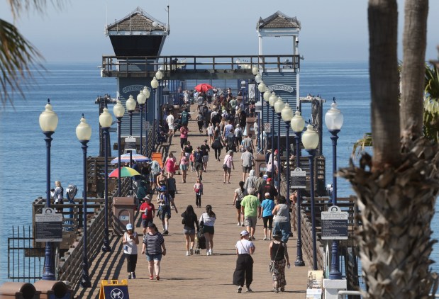 People walk on the Oceanside Pier in Oceanside in March. (Hayne Palmour IV / For The San Diego Union-Tribune)