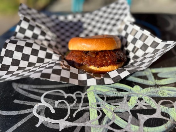 The regular hamburger from Hayes Burger in Barrio Logan is made with an Angus chuck patty, lettuce, a Roma tomato, grilled onions and house 1000 Island dressing on a brioche bun. (Abby Hamblin / The San Diego Union-Tribune)