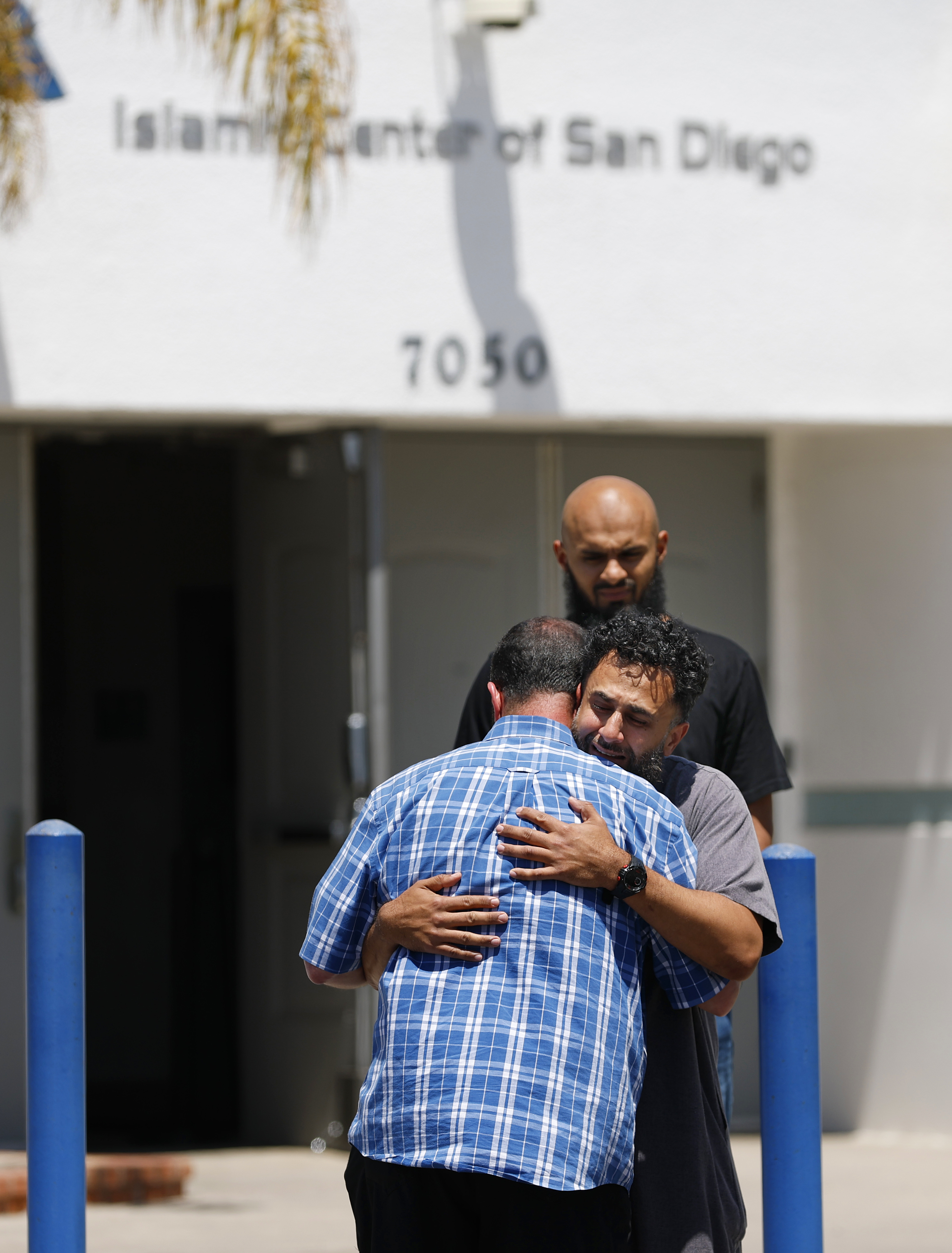Imam Taha Hassane (back to camera) hugs a man at...